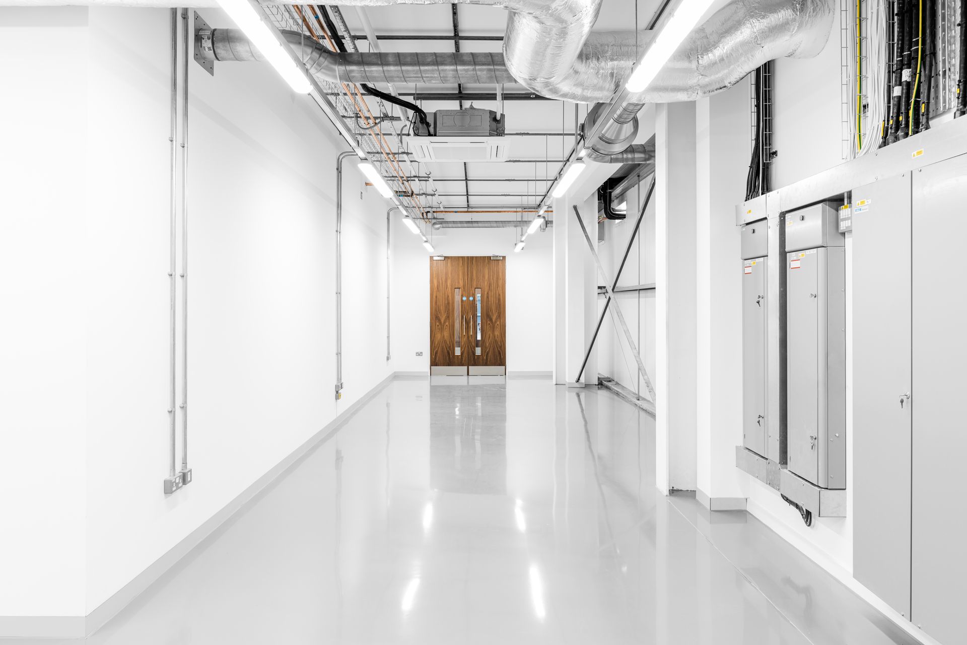 A long empty hallway in a building with white walls and a door.