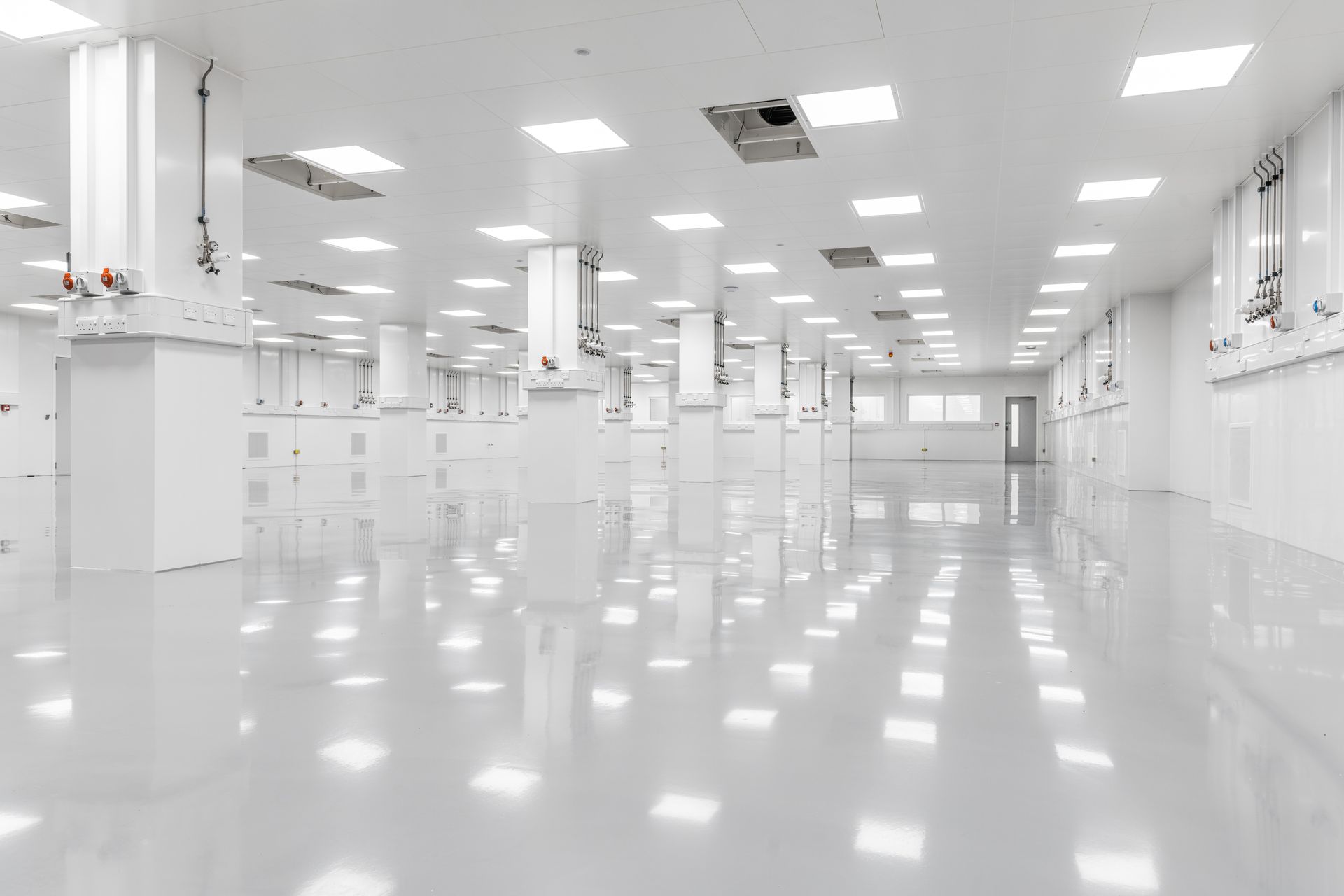 A large, bright cleanroom space with controls around the walls and on pillars.