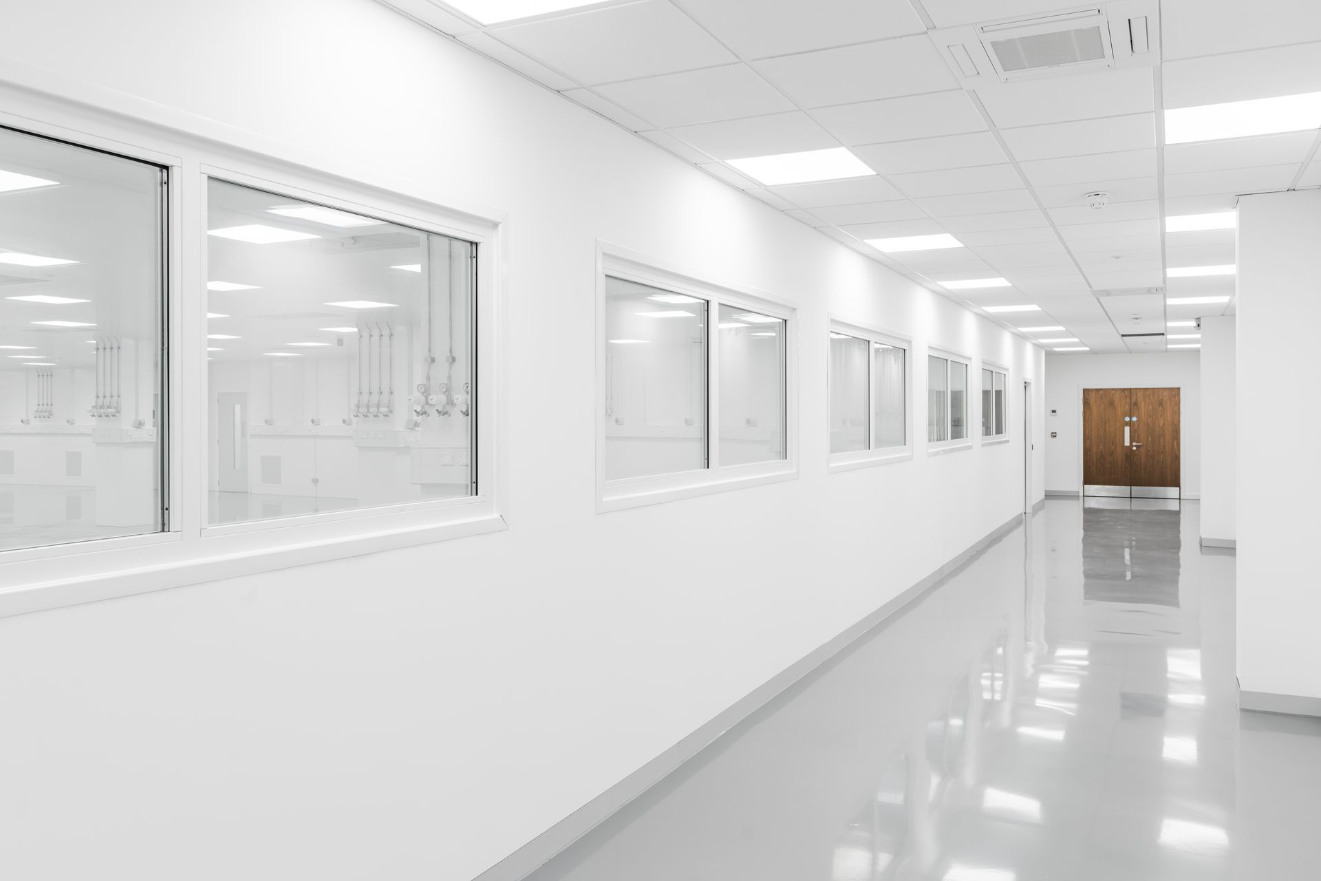 A long hallway in a clean room with lots of windows.