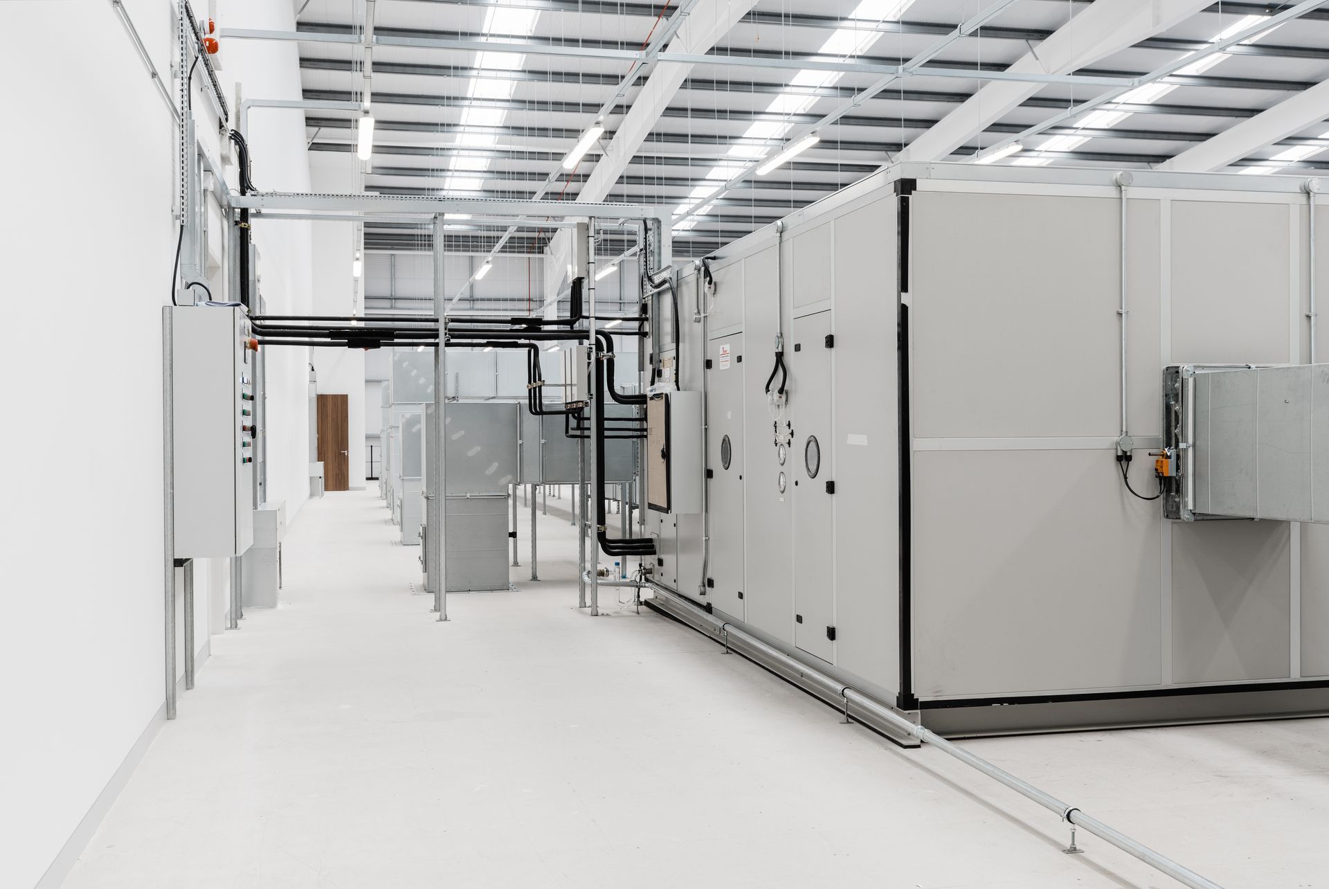 A large warehouse with a lot of white boxes and pipes.