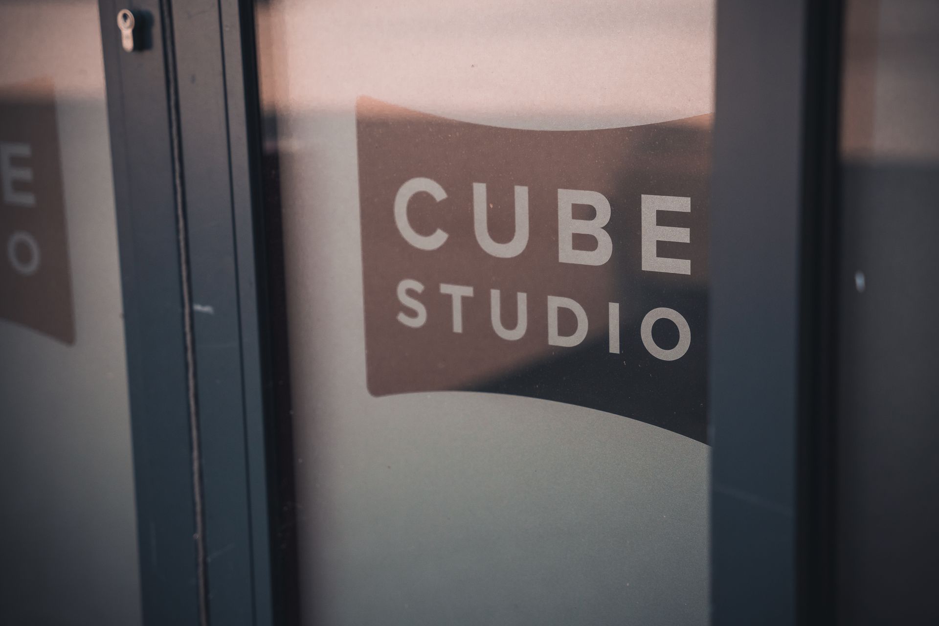A close up of a cube studio sign on a glass door.