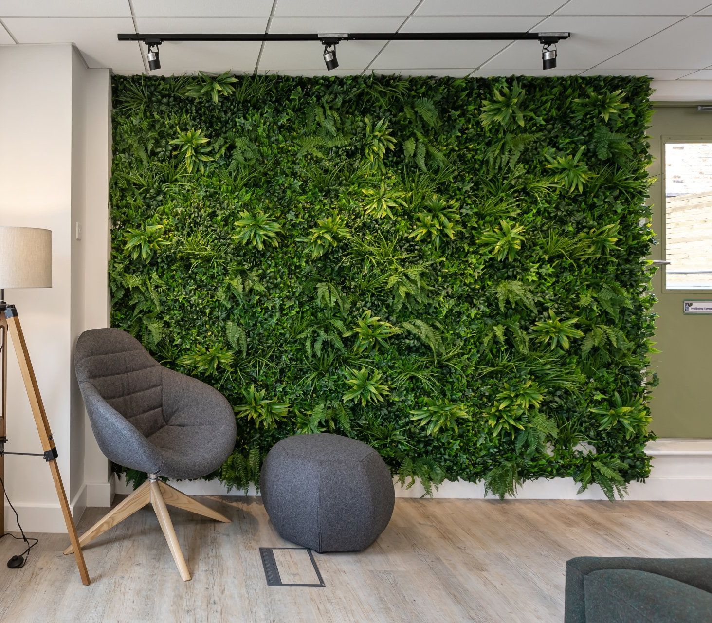 A living room with a chair and ottoman in front of a green wall.