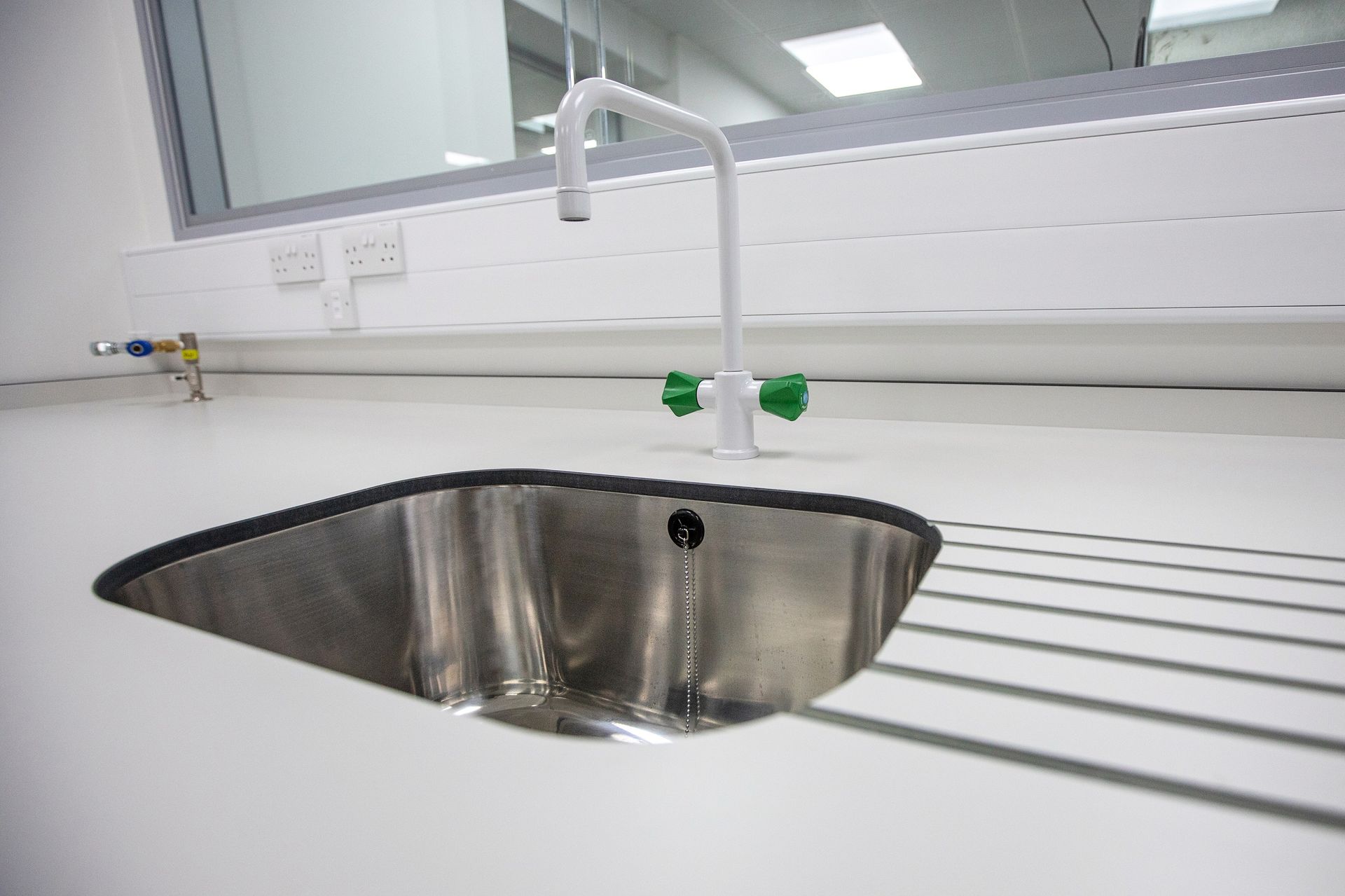 A stainless steel sink with a white faucet and green handles.