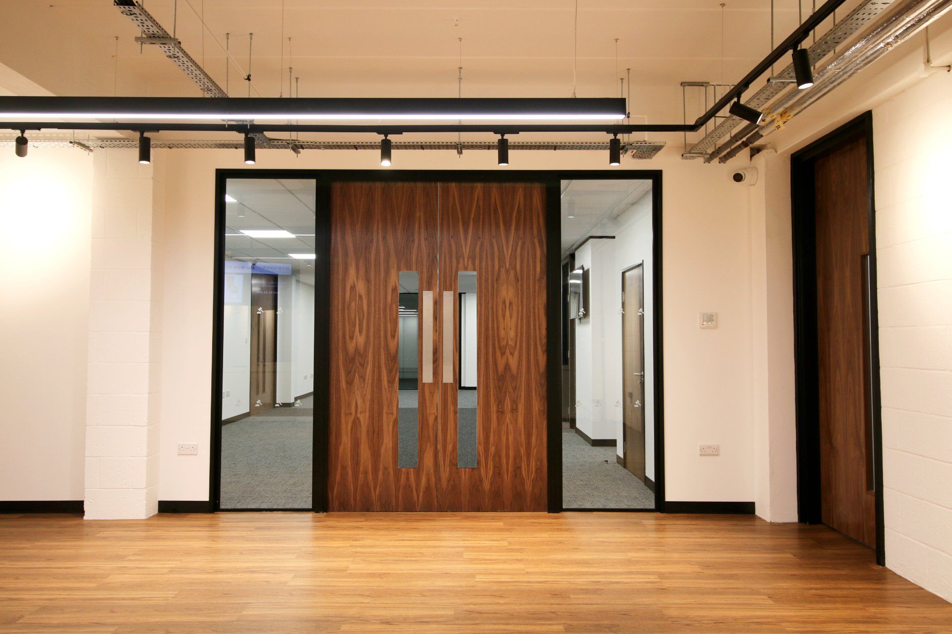 a large empty room with wooden floors and a wooden door .