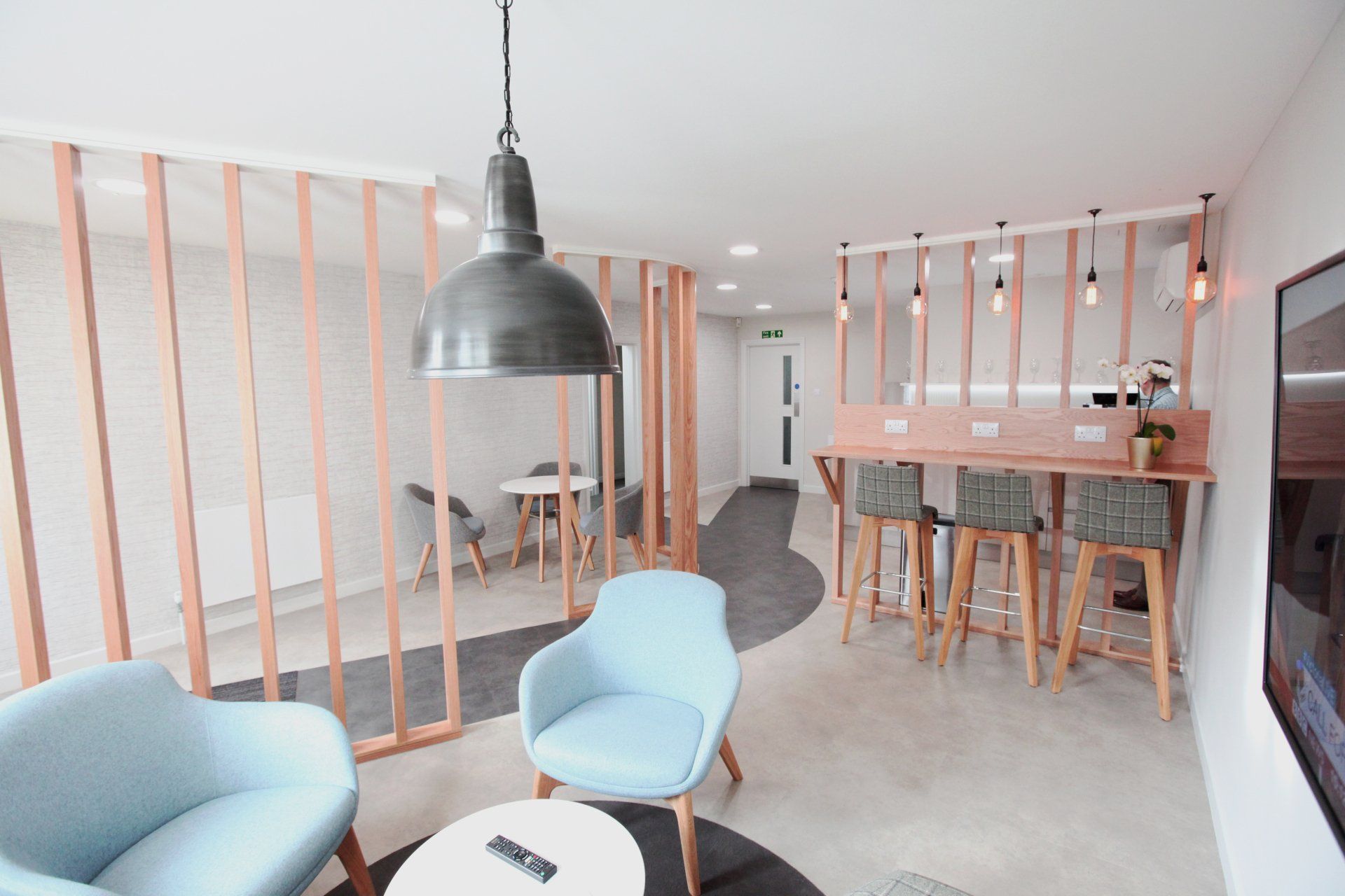 Breakout area with pastel pink wood and pastel blue chairs by Glenside