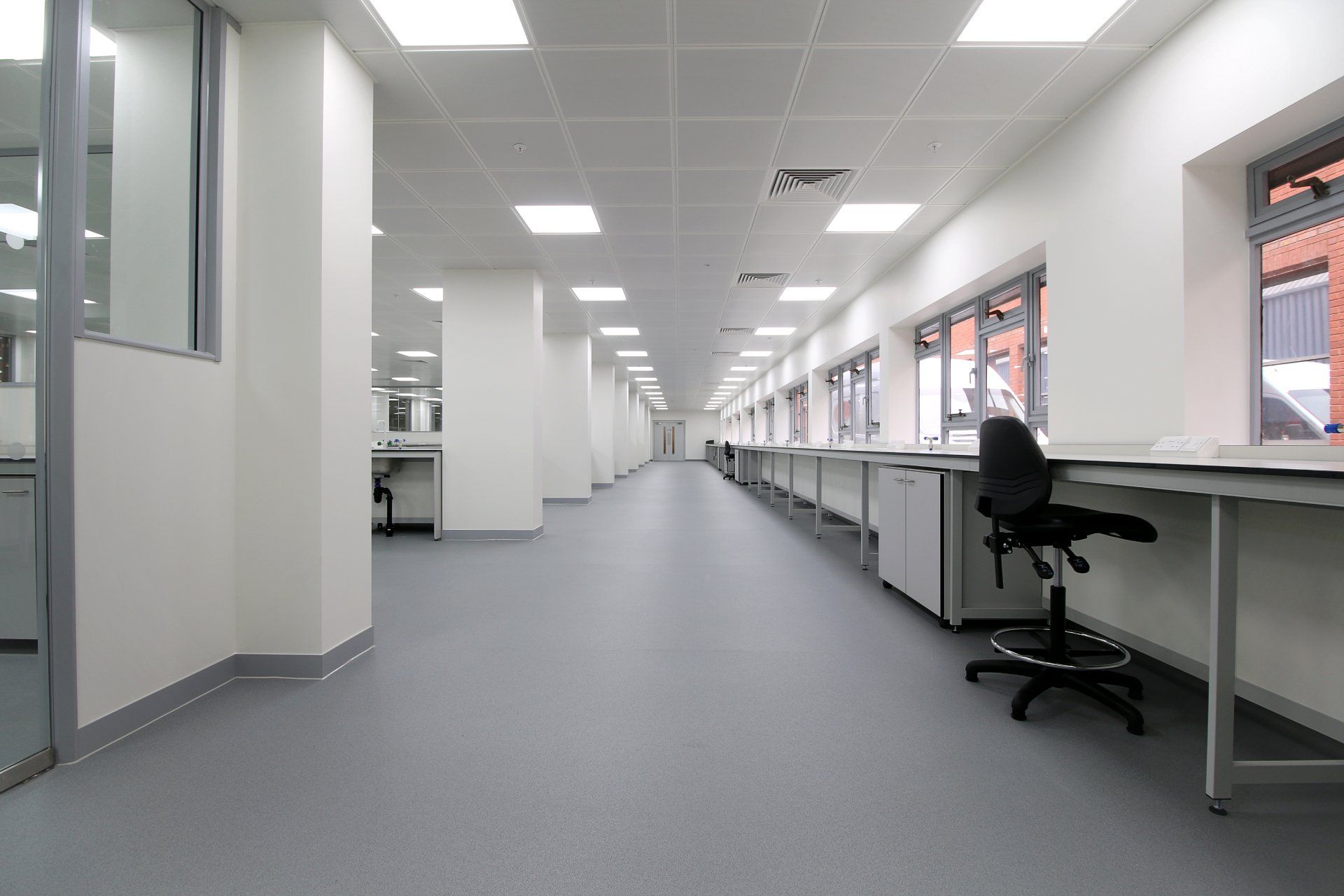 A long hallway in a building with desks and chairs.
