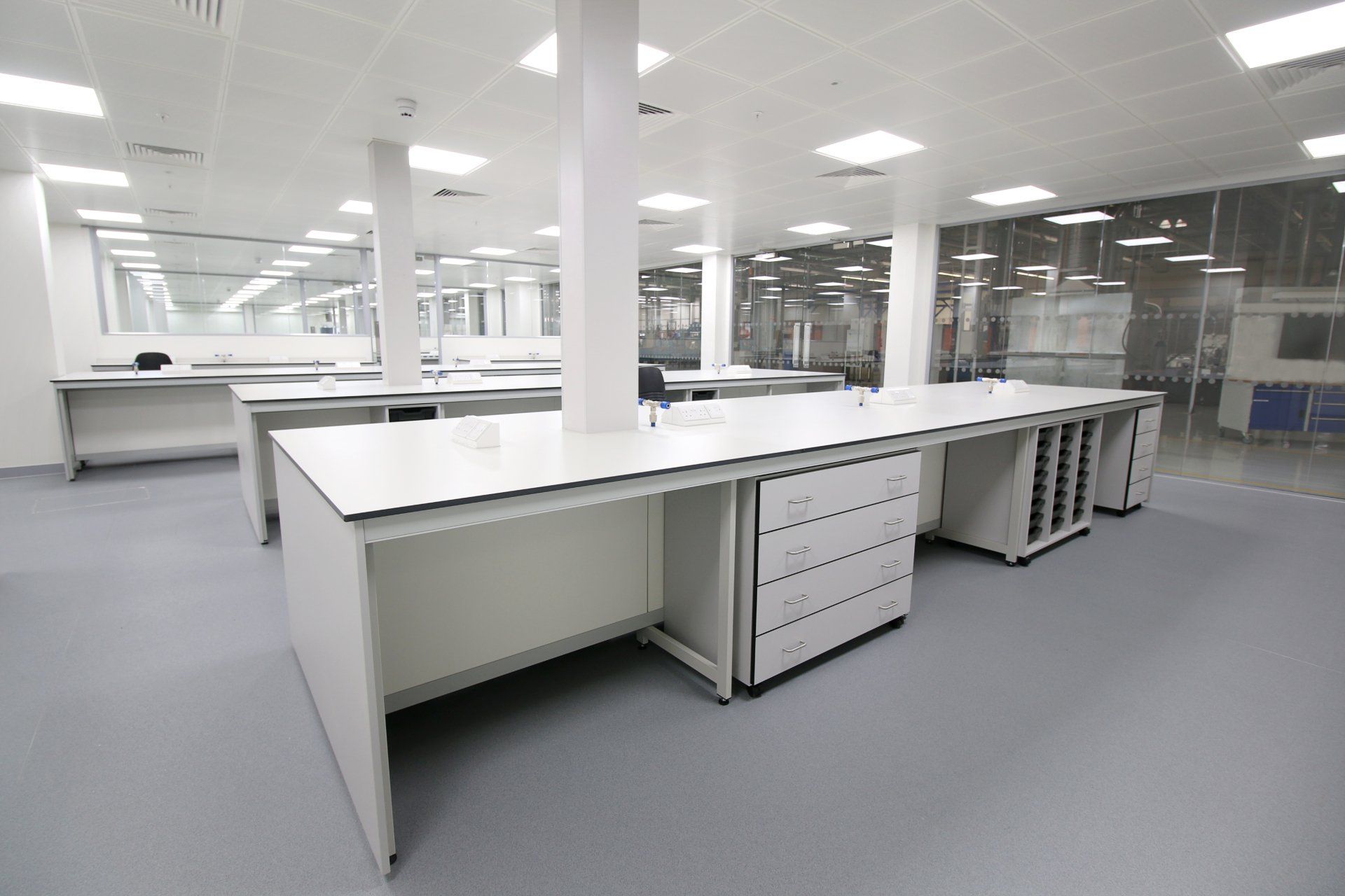 A large room with a lot of white desks and drawers