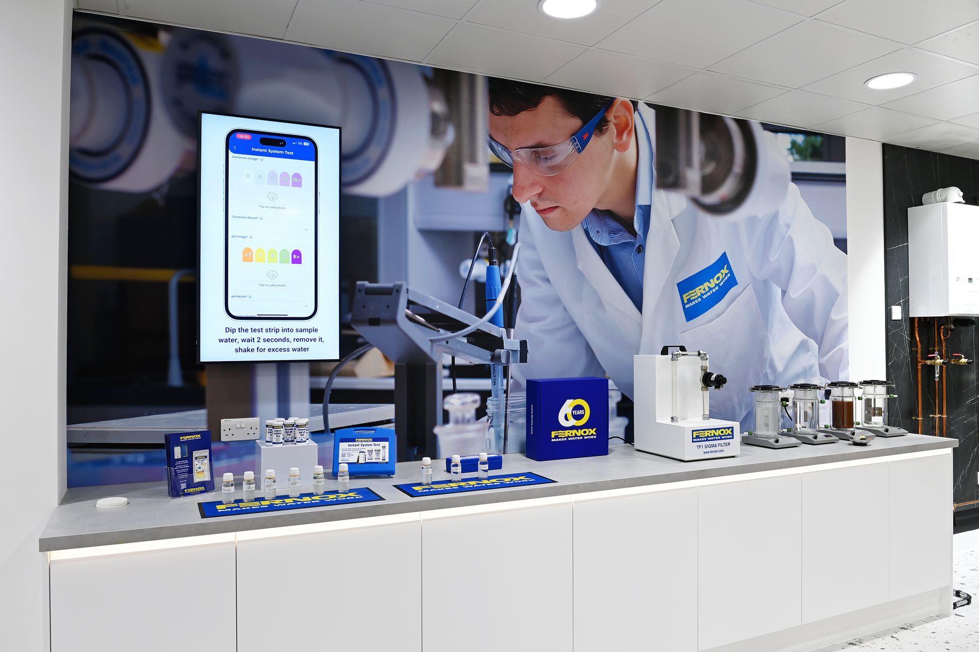 Display with scientific equipment and a man in a lab coat, plus a phone with an app interface.