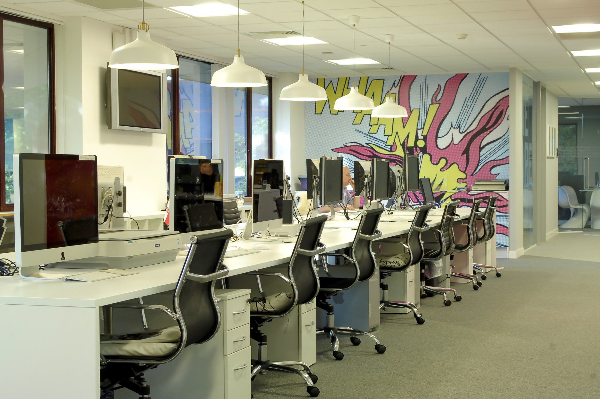a row of desks with computers and chairs in an office