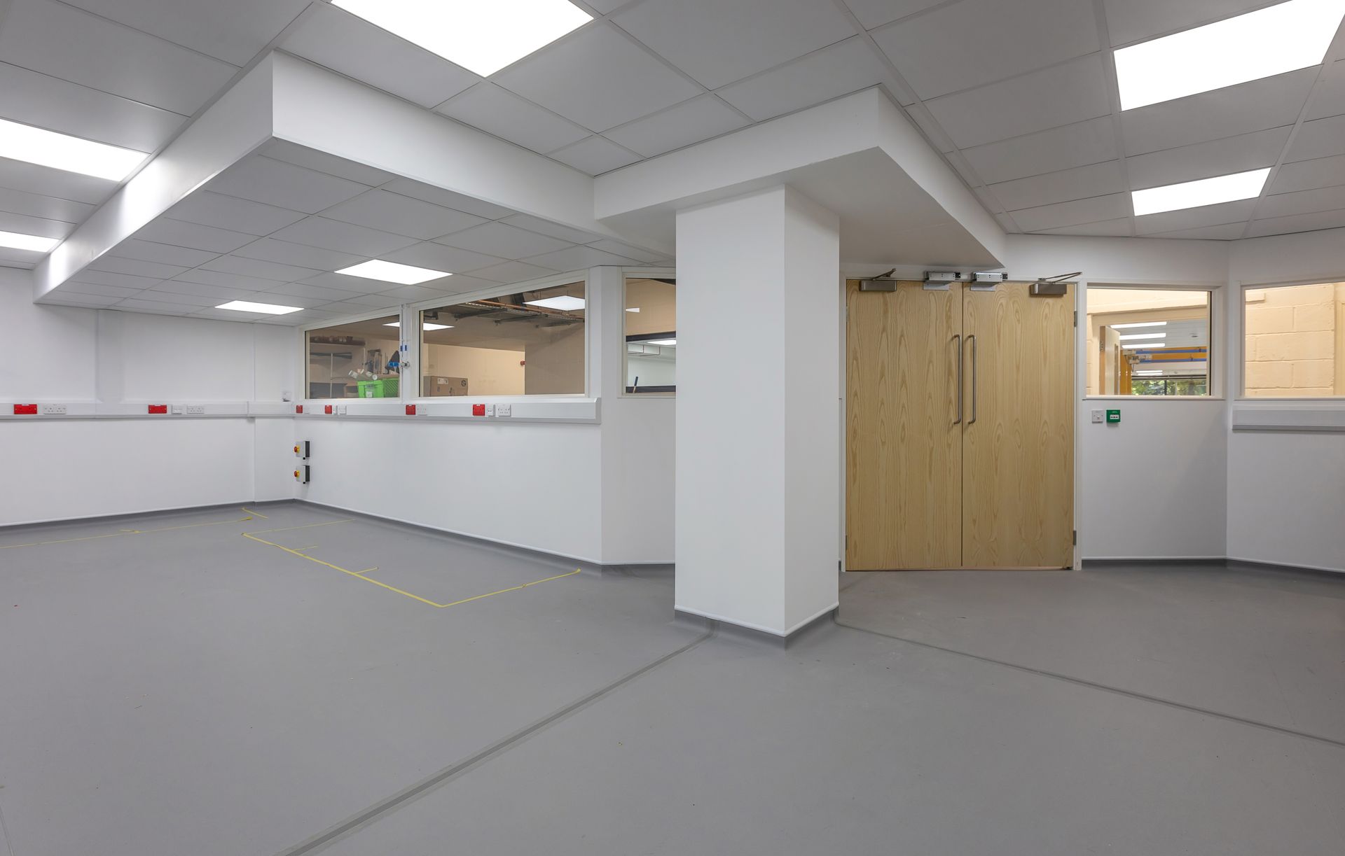 A large empty room with a wooden door and white walls.