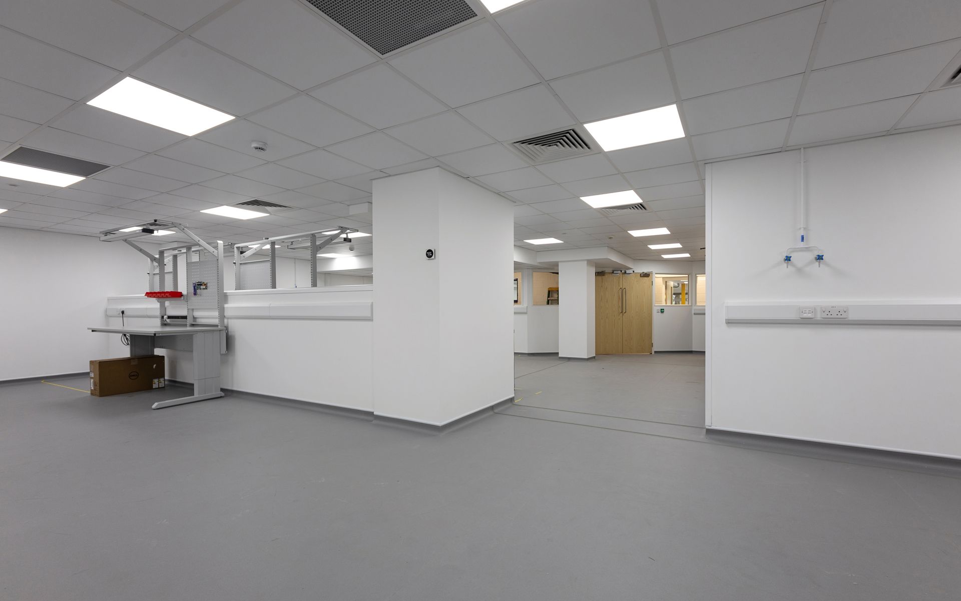 A large empty room with white walls and a gray floor.