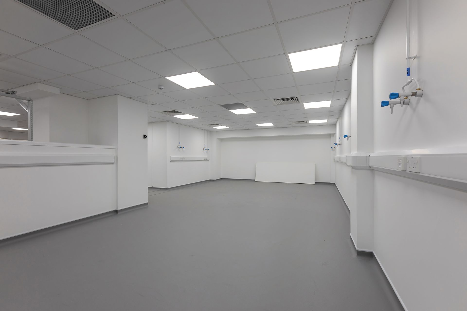 A large empty room with a gray floor and white walls.