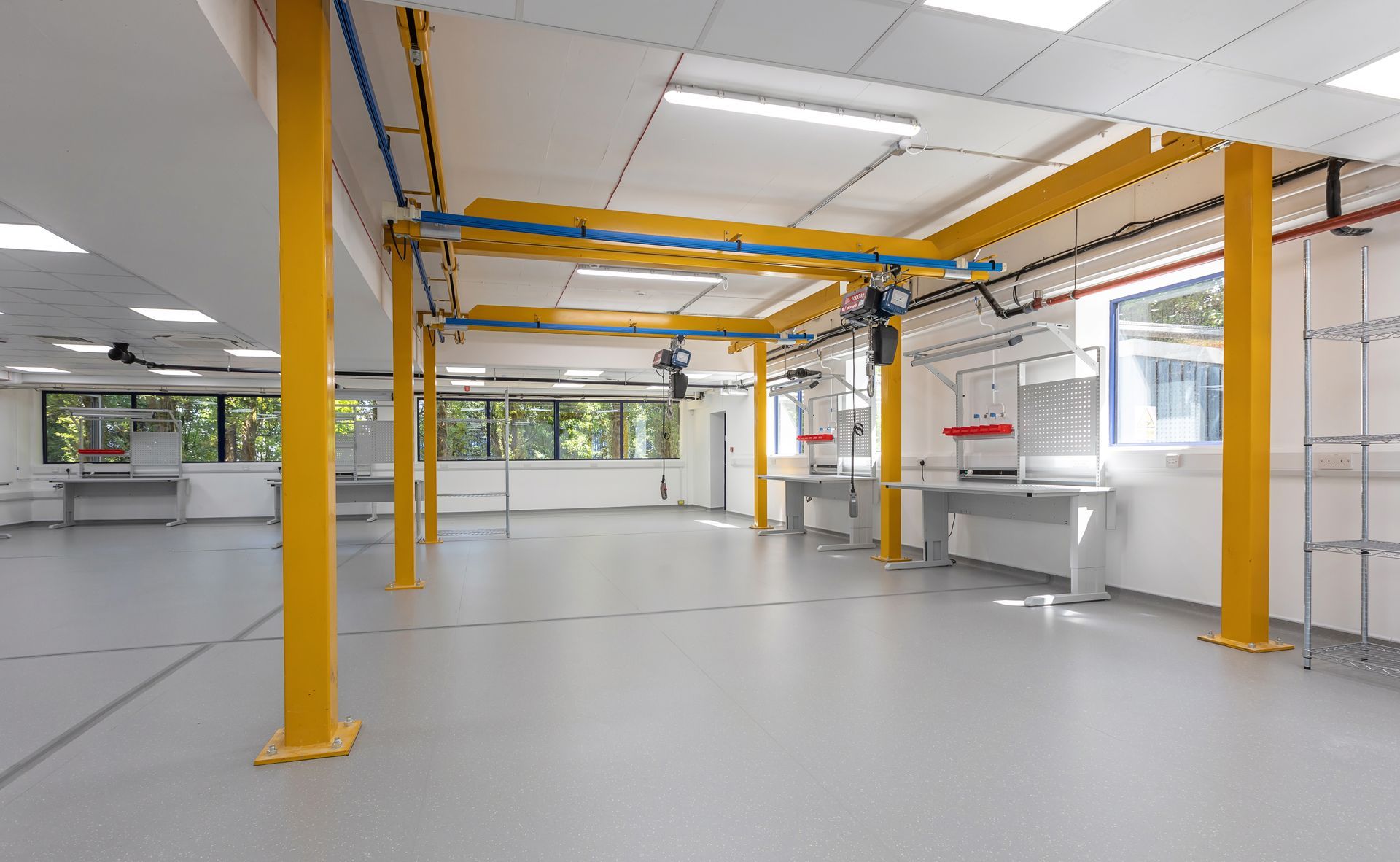 A large empty room with yellow pillars and a crane hanging from the ceiling.