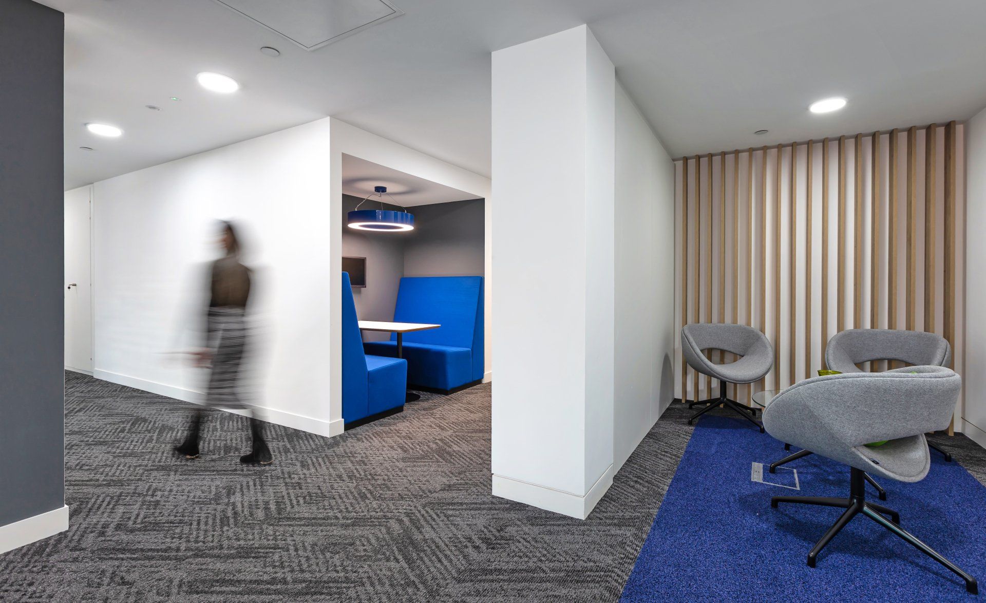A blurry picture of a person walking through a hallway in an office.