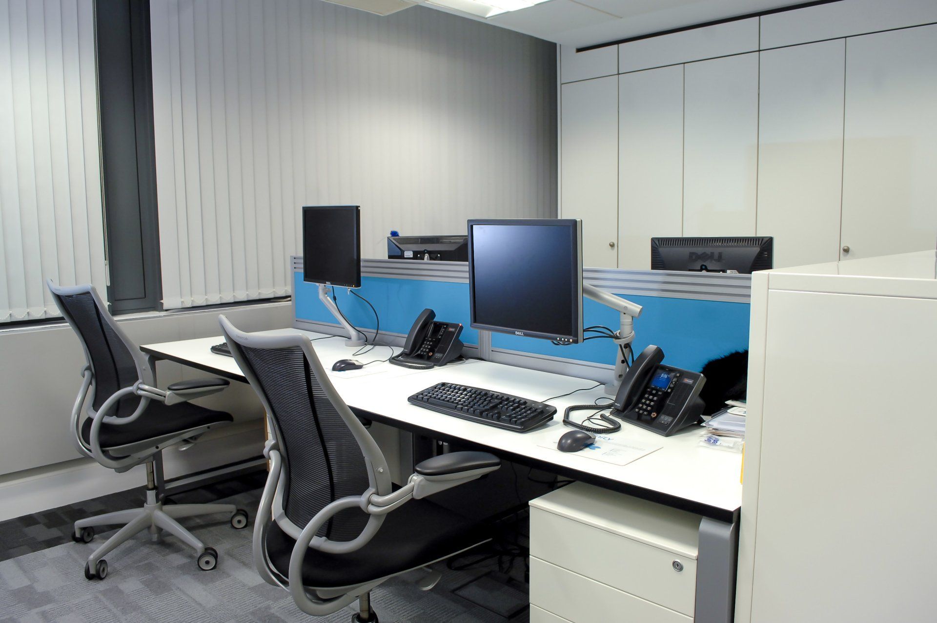 A row of desks with computers and chairs in an office