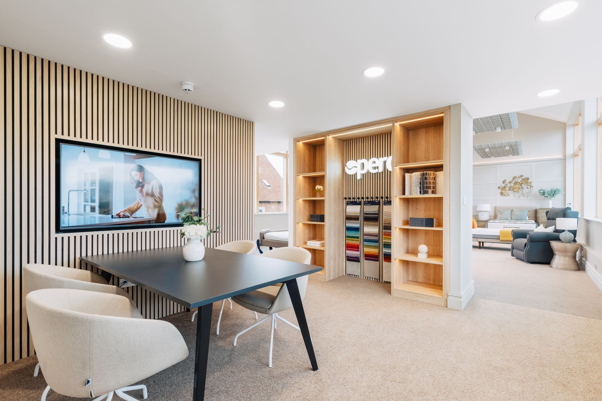 A room with a table and chairs and a flat screen tv on the wall.