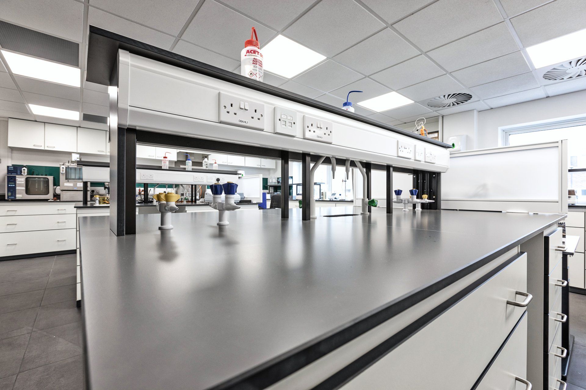 An empty laboratory with a long counter and a lot of equipment.