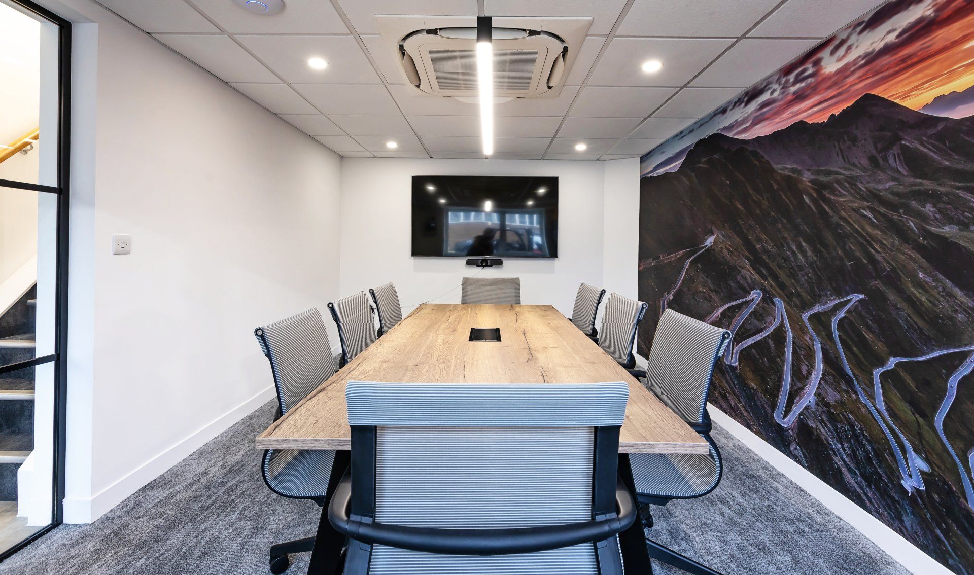 A conference room with a long table and chairs and a television on the wall.