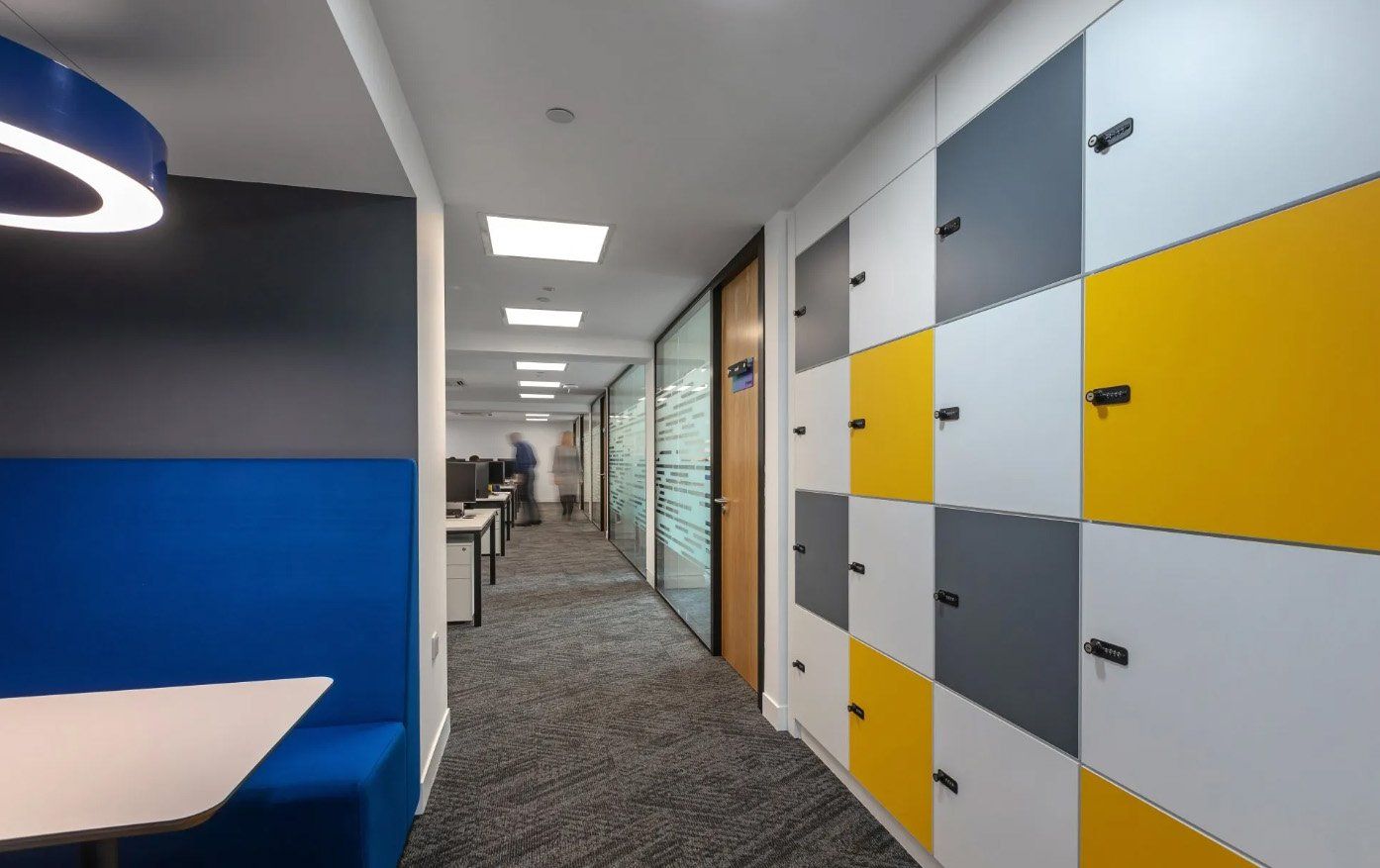 A hallway with lockers on the wall and a blue booth.