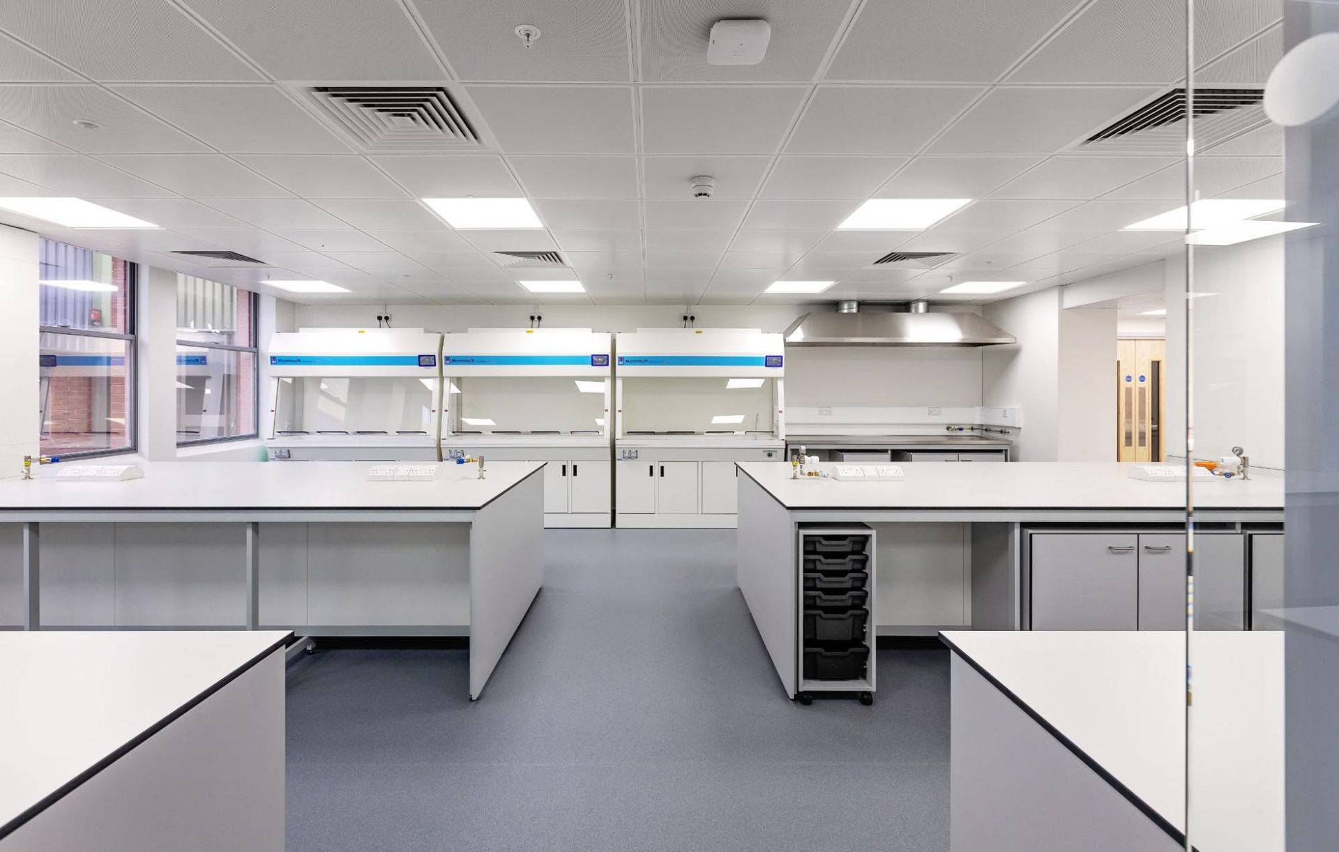 A large empty laboratory with a lot of tables and cabinets.