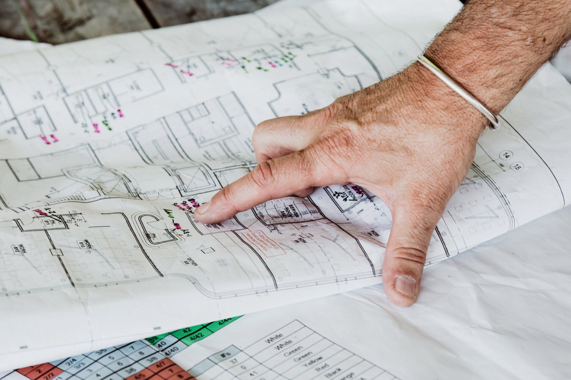 Man's hand pointing to blueprint