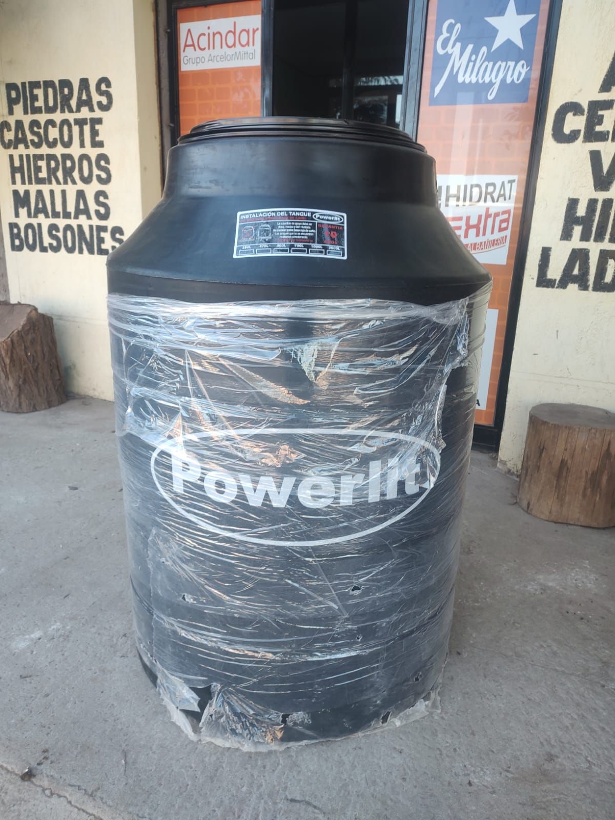 Un tanque de agua negra está envuelto en plástico y se encuentra frente a una tienda.