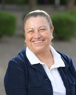 A smiling woman wearing a blue jacket and white shirt