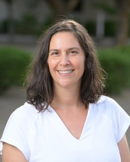 A woman in a white shirt is smiling for the camera.