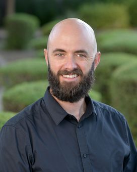 A bald man with a beard wearing a black shirt is smiling for the camera.