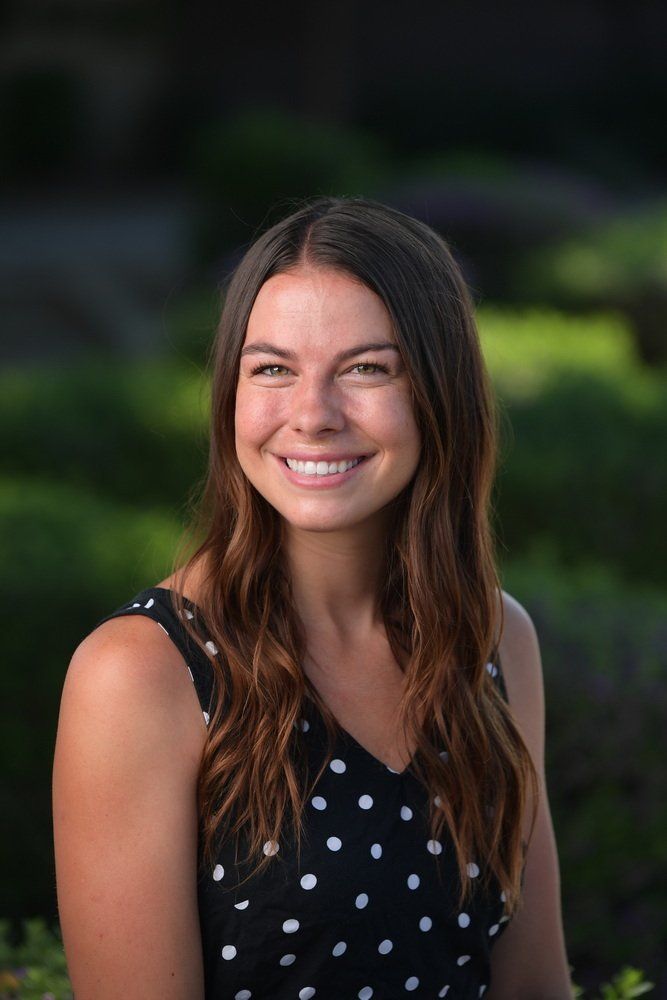 A woman in a black tank top is smiling for the camera.