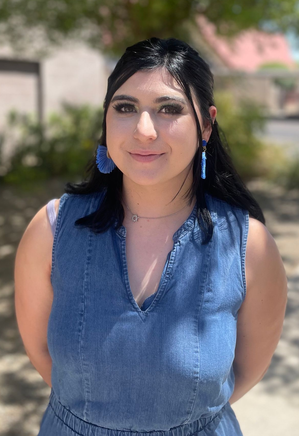 A woman in a striped shirt and overalls is smiling for the camera.