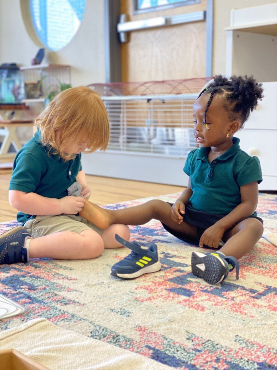 A boy and a girl are sitting on the floor helping each other to get dressed