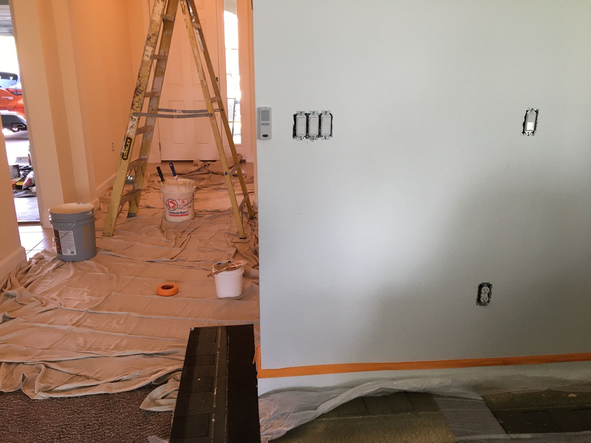 Home interior prepared for residential painting services, with drop cloths, ladders, and paint supplies for wall painting.