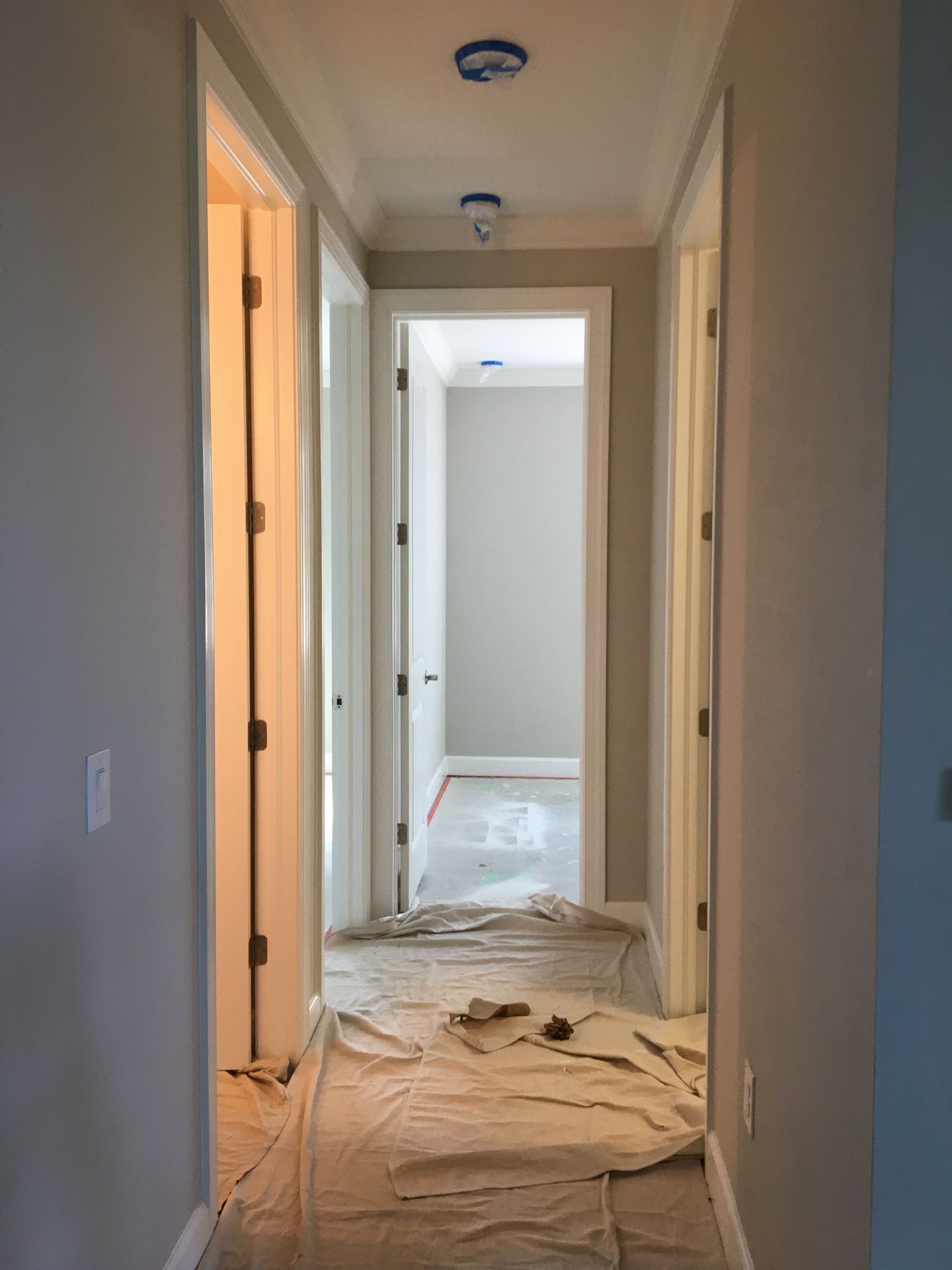 Home interior with drop cloths and masking tape for residential exterior painting preparation.