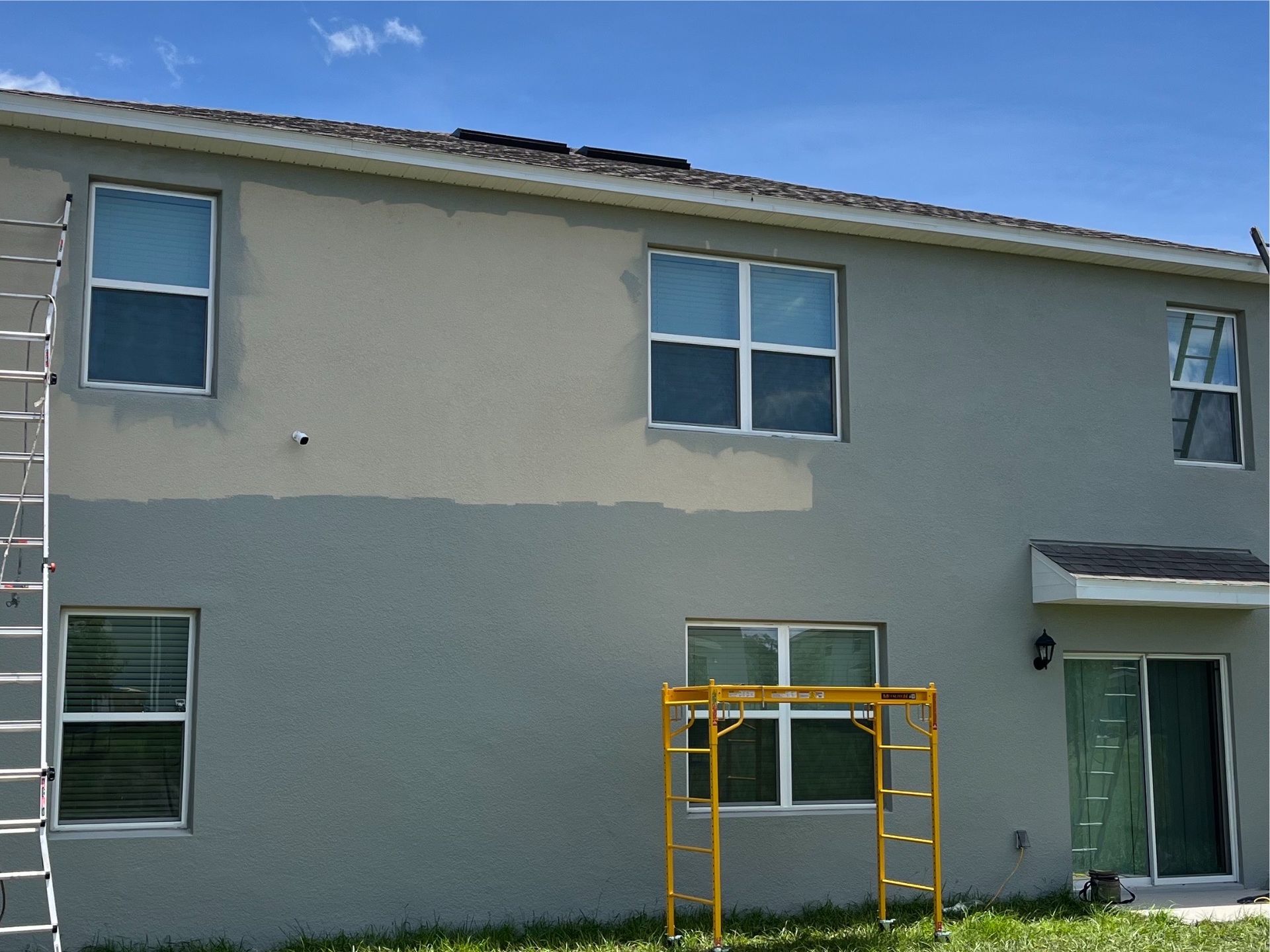 A house that is being painted with a yellow ladder in front of it