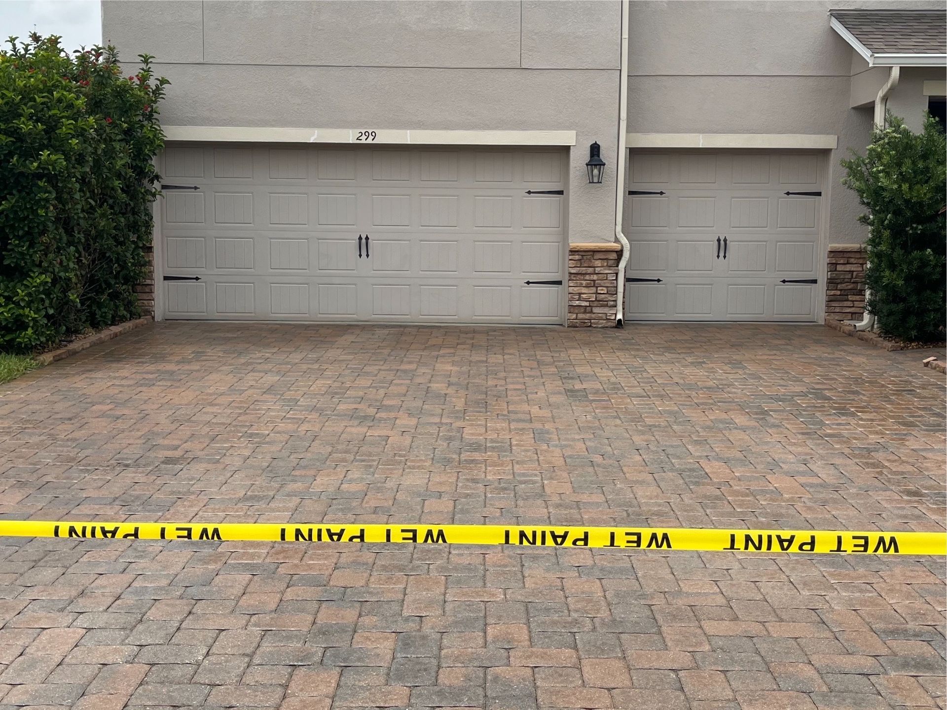A brick driveway with a yellow tape that says wet paint