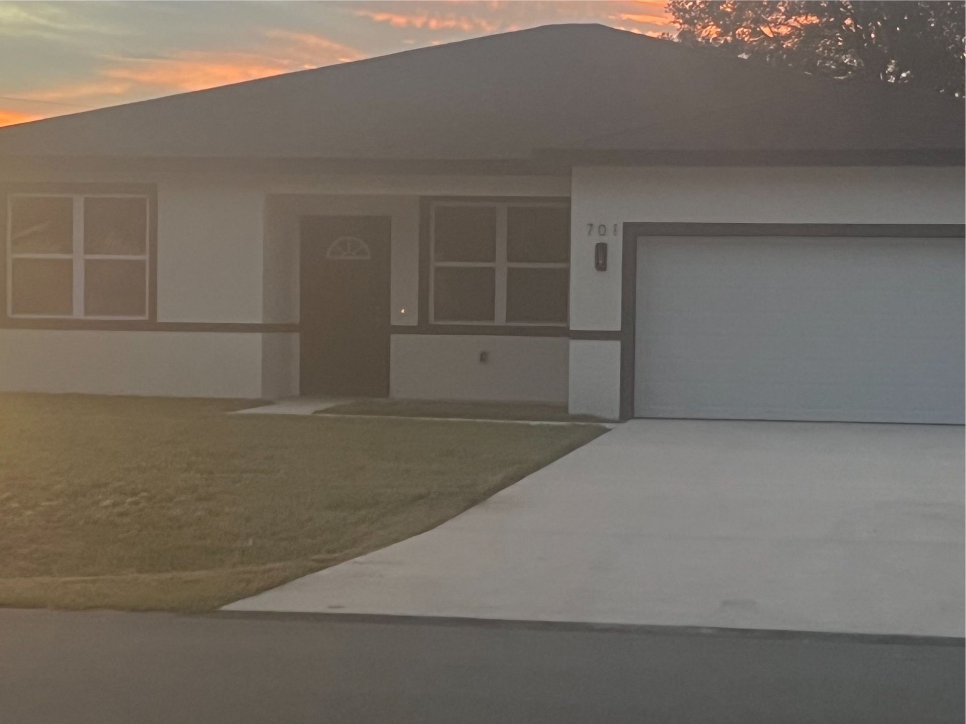A house with a garage and a driveway at sunset.