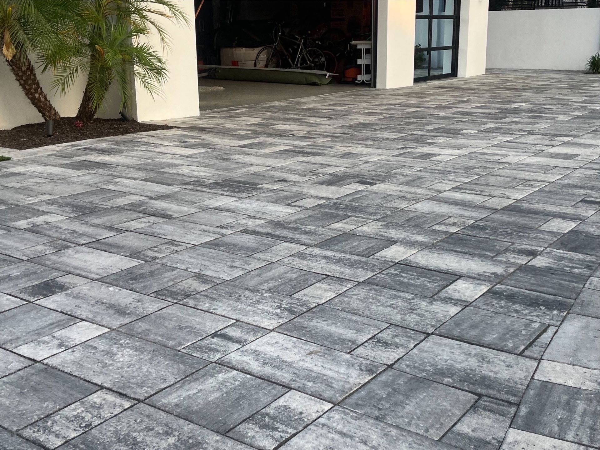 A gray and white brick driveway with a garage in the background.