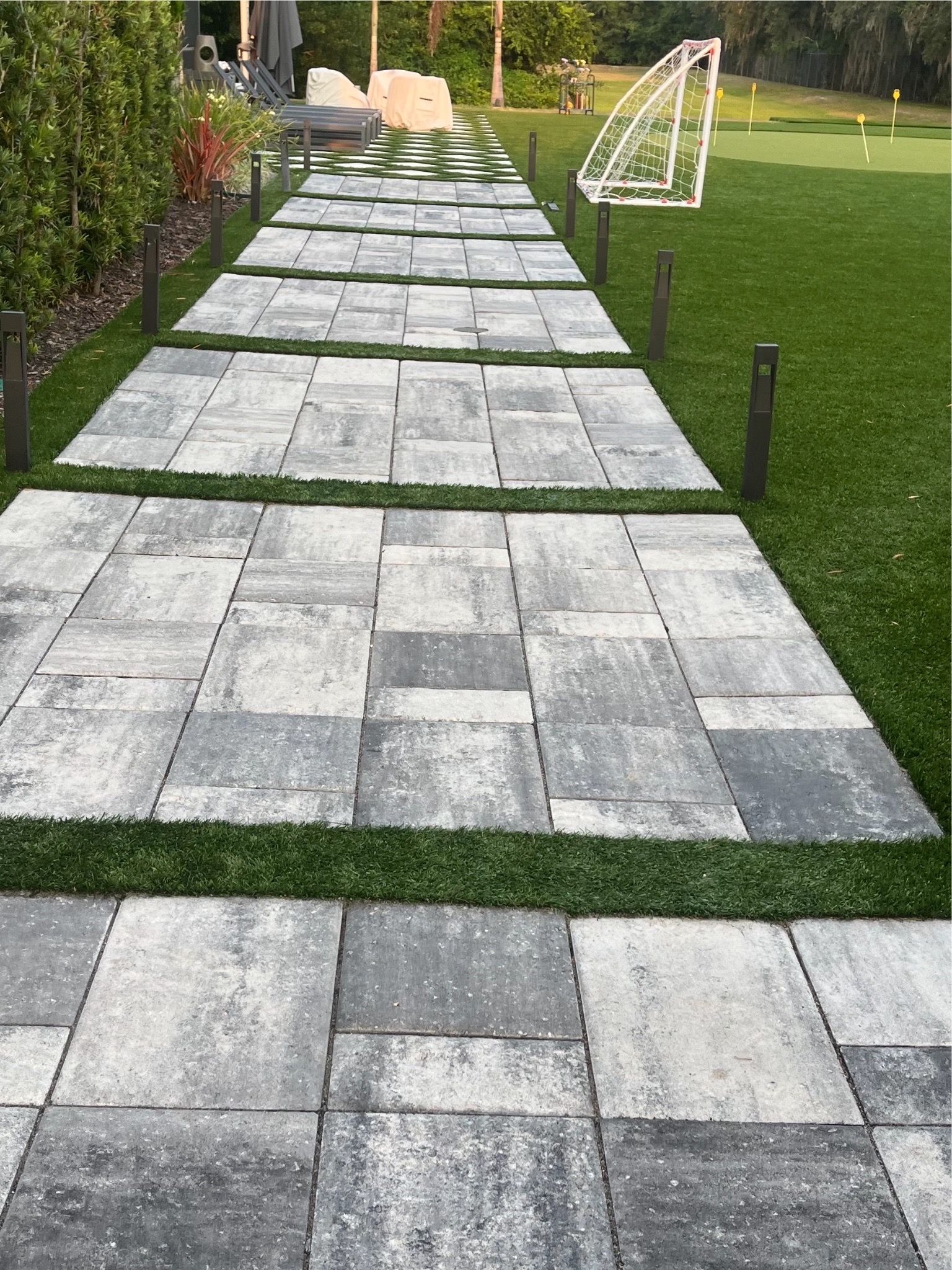 A walkway leading to a soccer field with a soccer goal in the background.