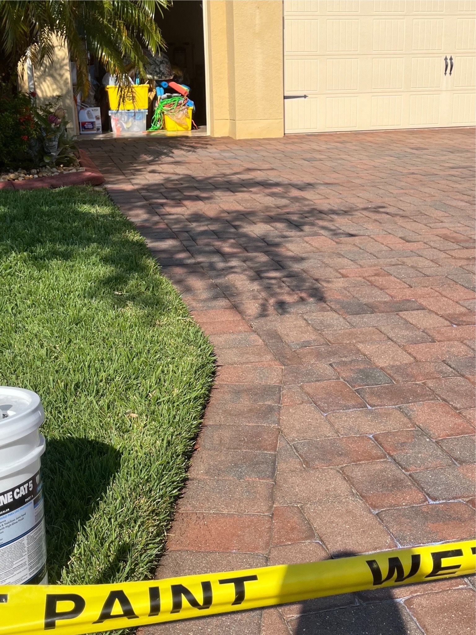 A bucket of paint is sitting next to a yellow tape that says paint on it.