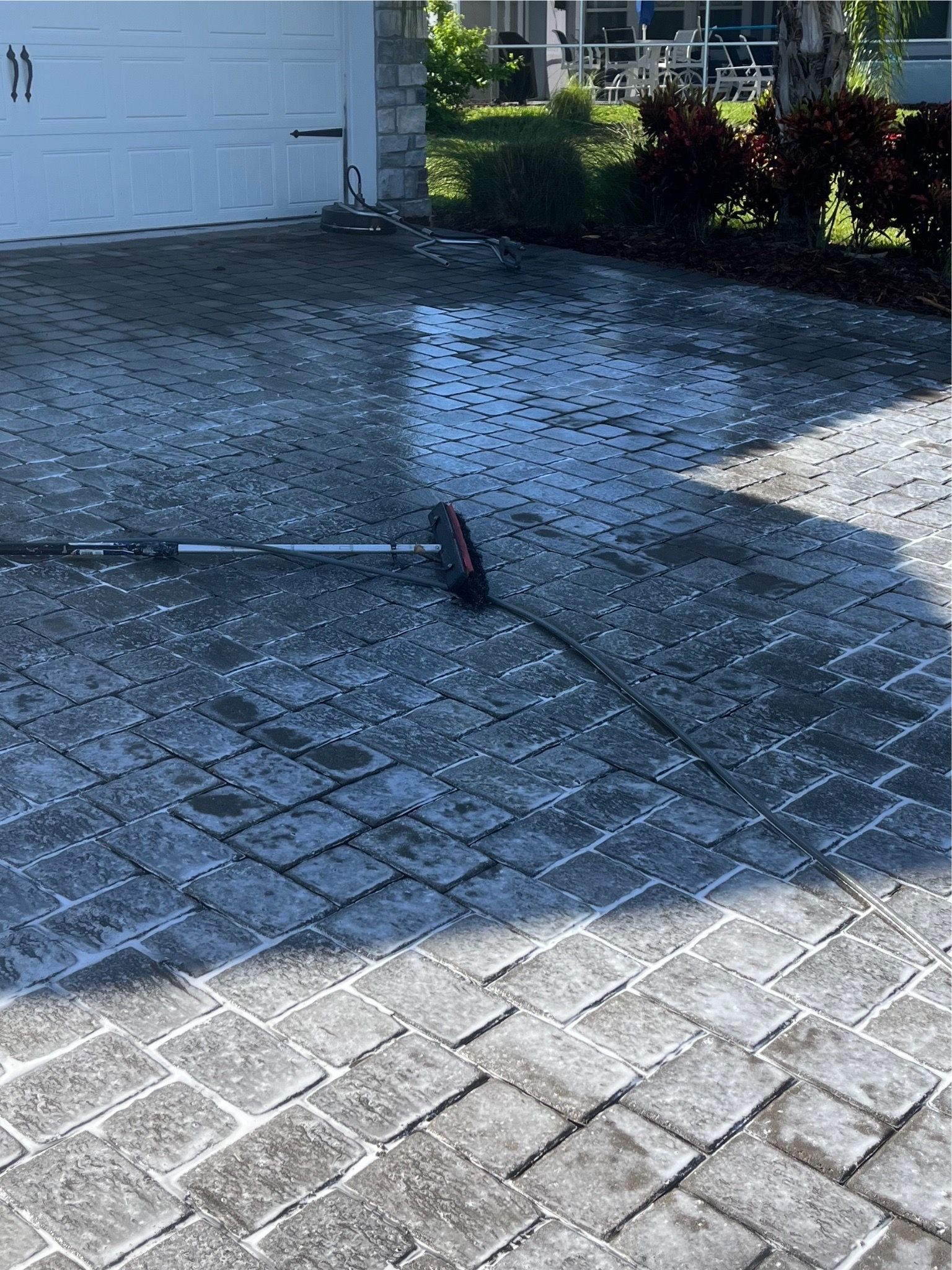 A person is cleaning a driveway with a broom.