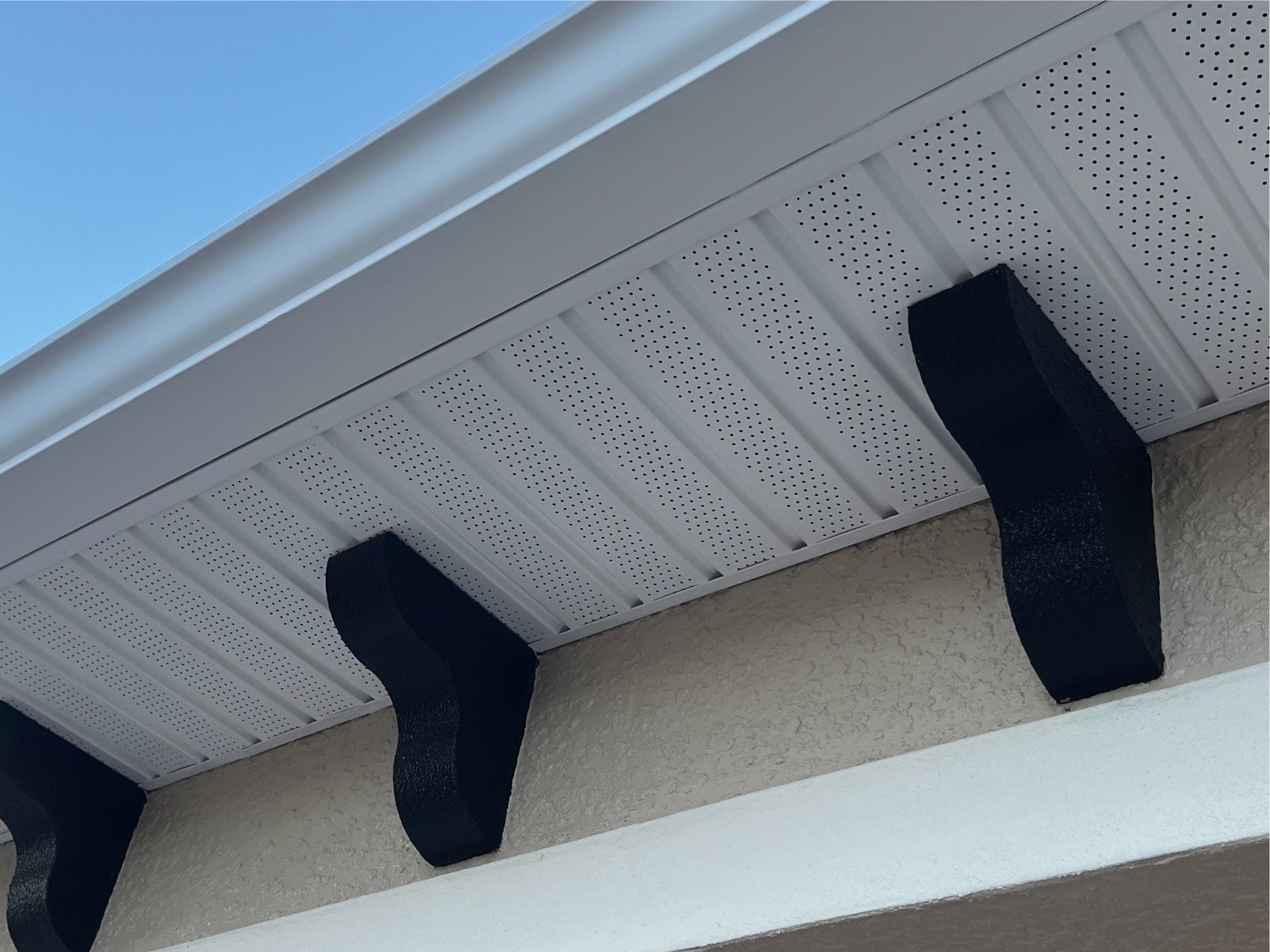 The roof of a house has a white gutter and black beams