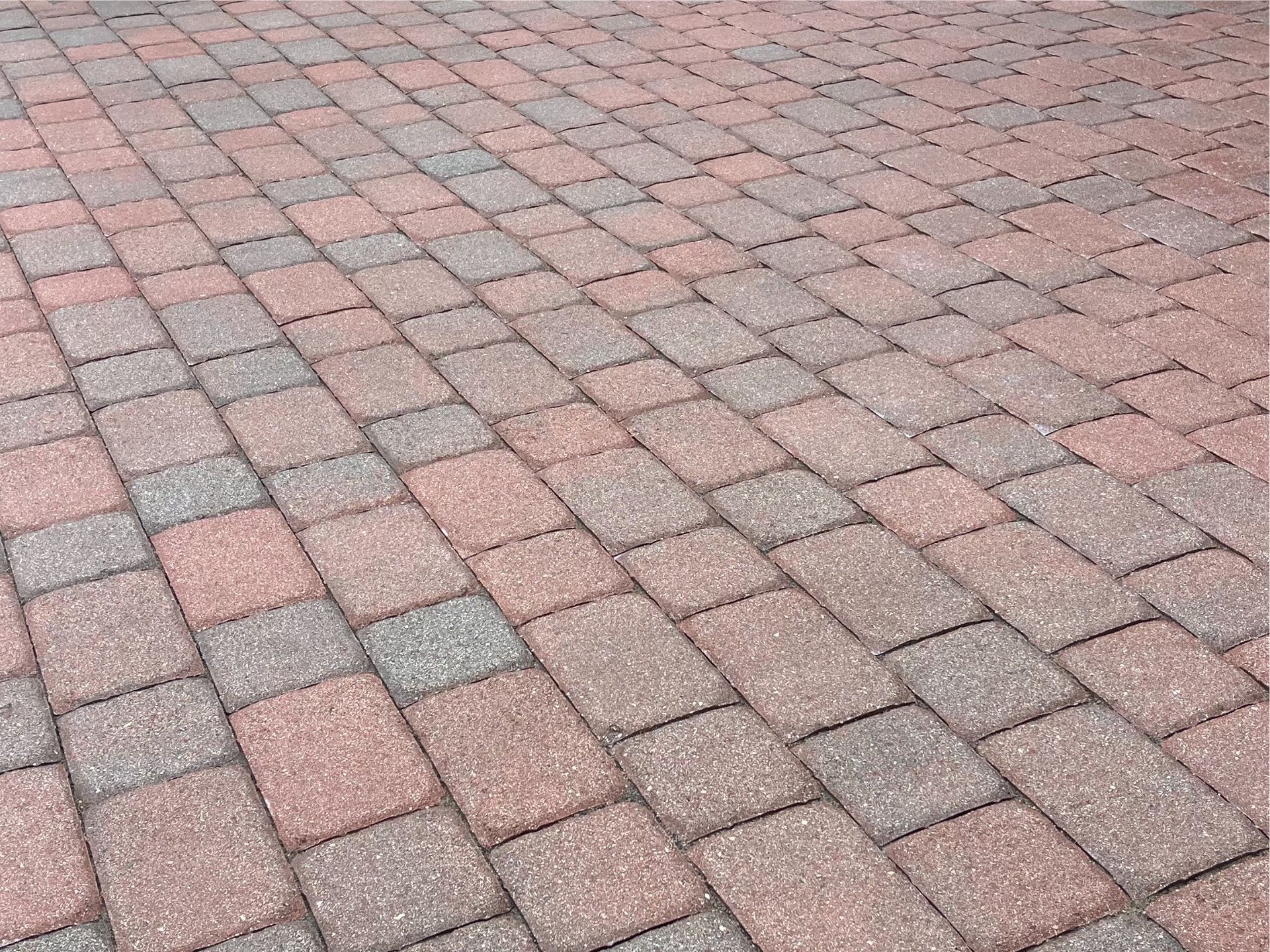 A close up of a brick pavement with a diagonal pattern.