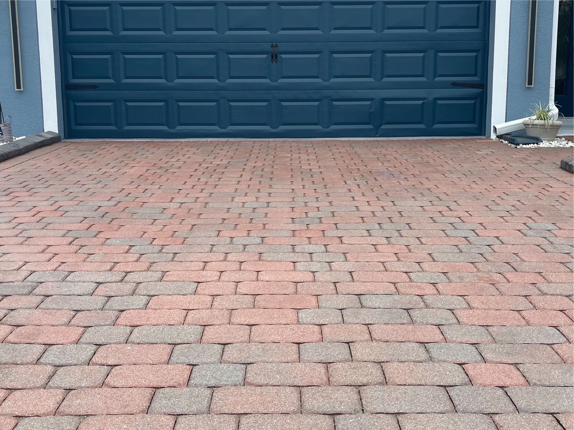 A brick driveway with a blue garage door in the background.