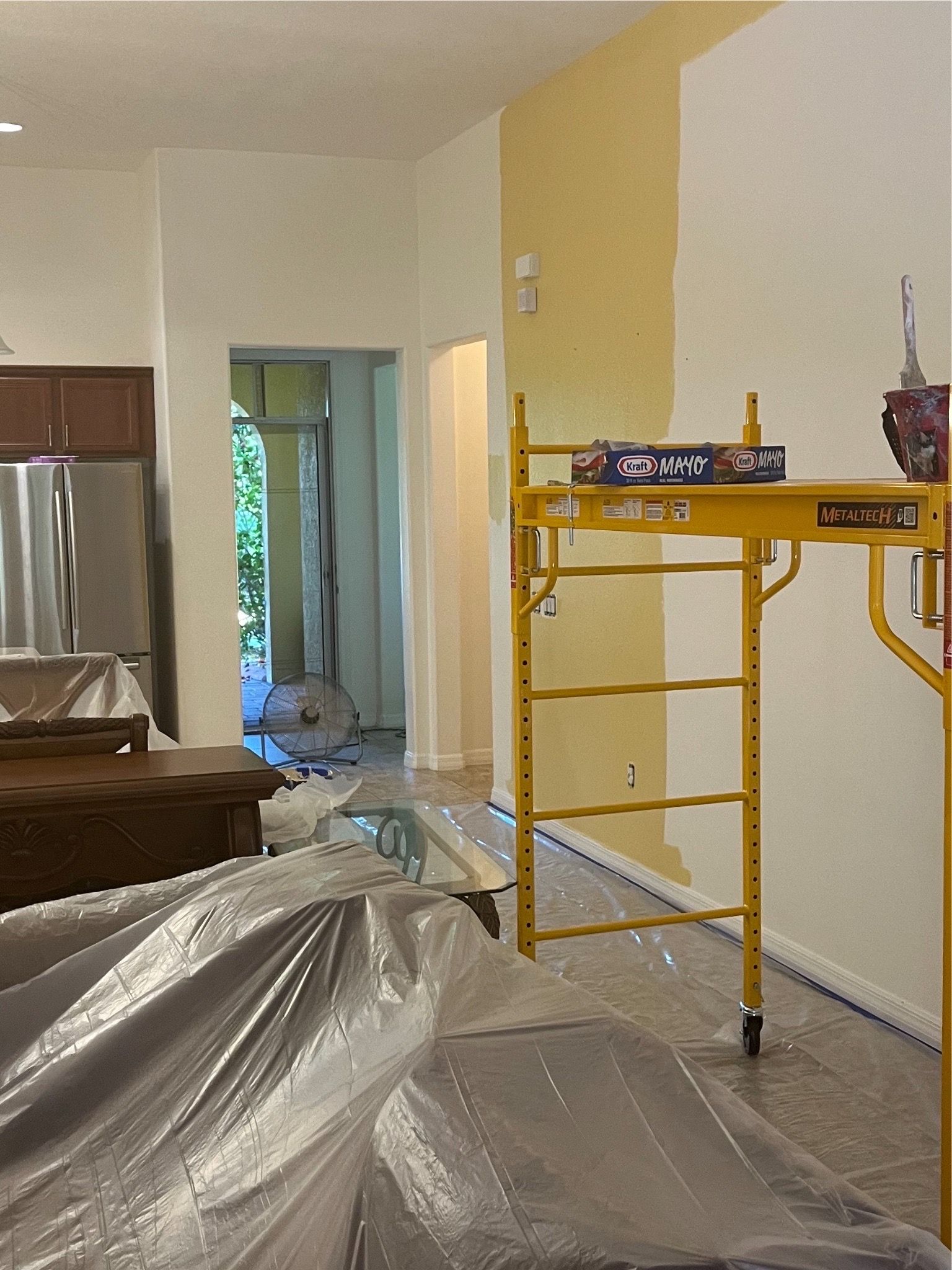Interior kitchen with scaffolding and plastic covers, prepared for residential interior painting services.