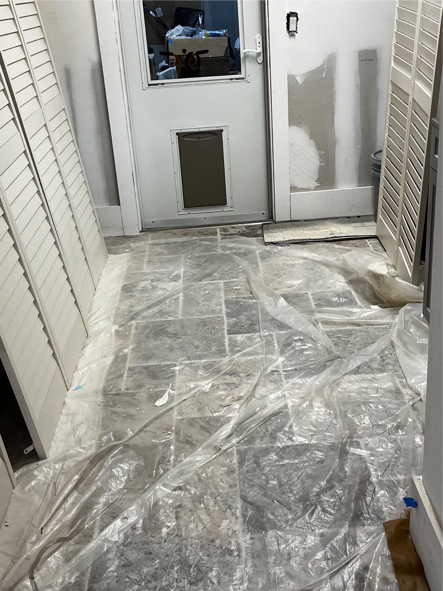 A room with a tiled floor and a door covered in plastic.