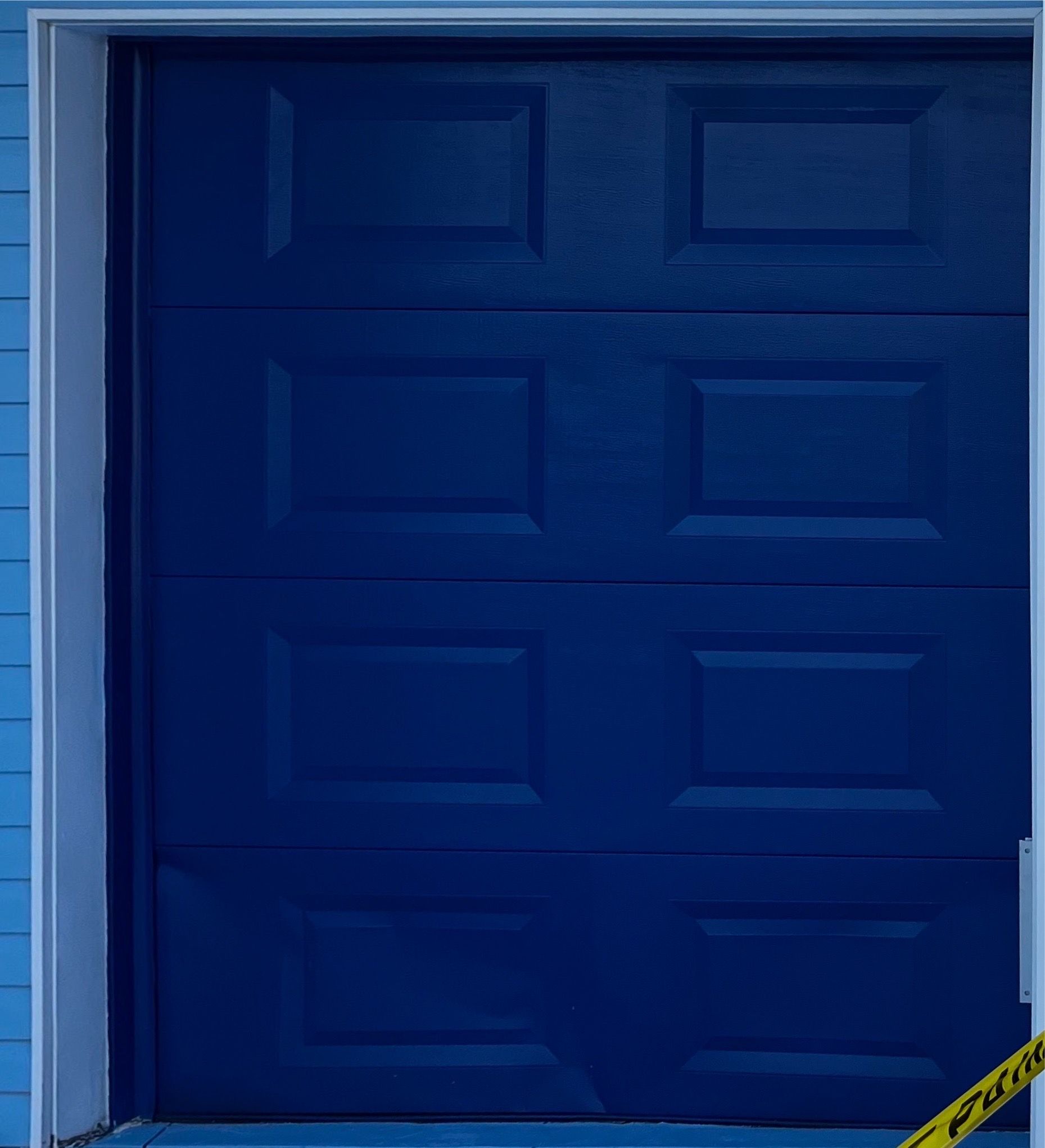 A blue garage door with a yellow caution tape around it