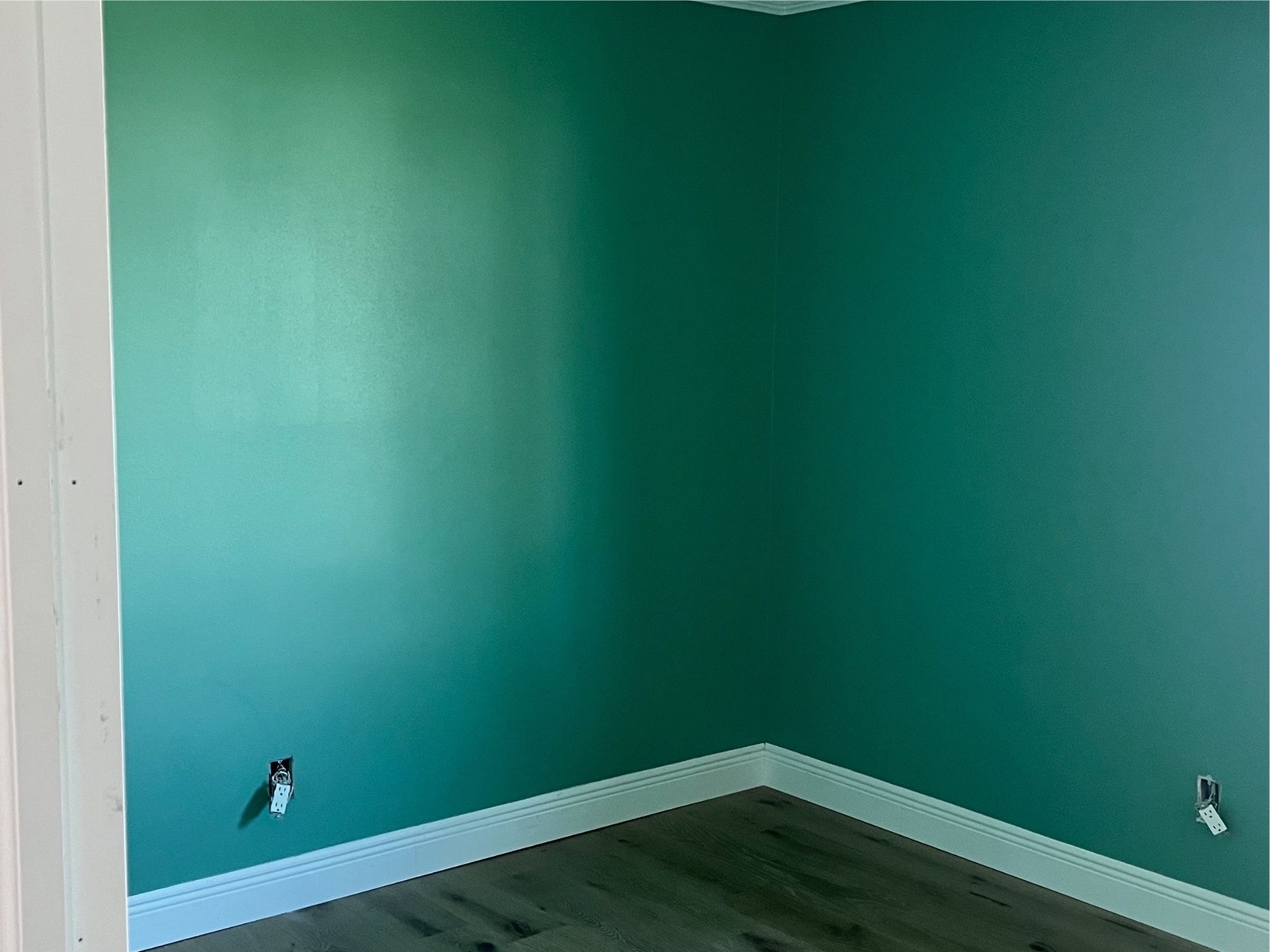 A room with green walls and a wooden floor.