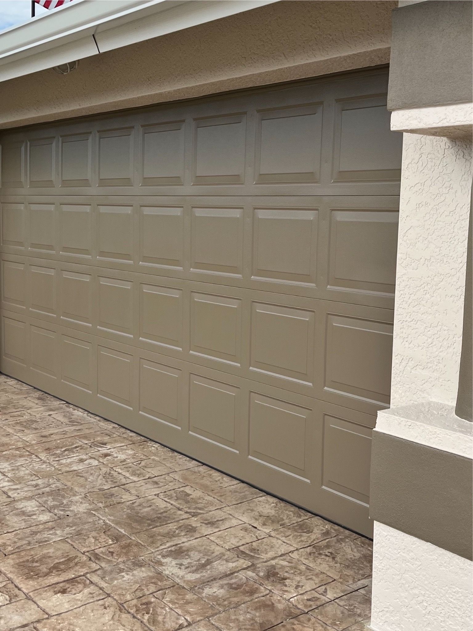 A large tan garage door is sitting on the side of a house