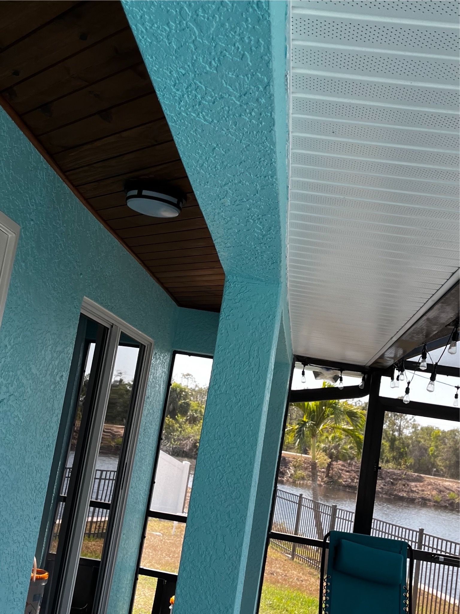 A blue porch with a chair and a ceiling.
